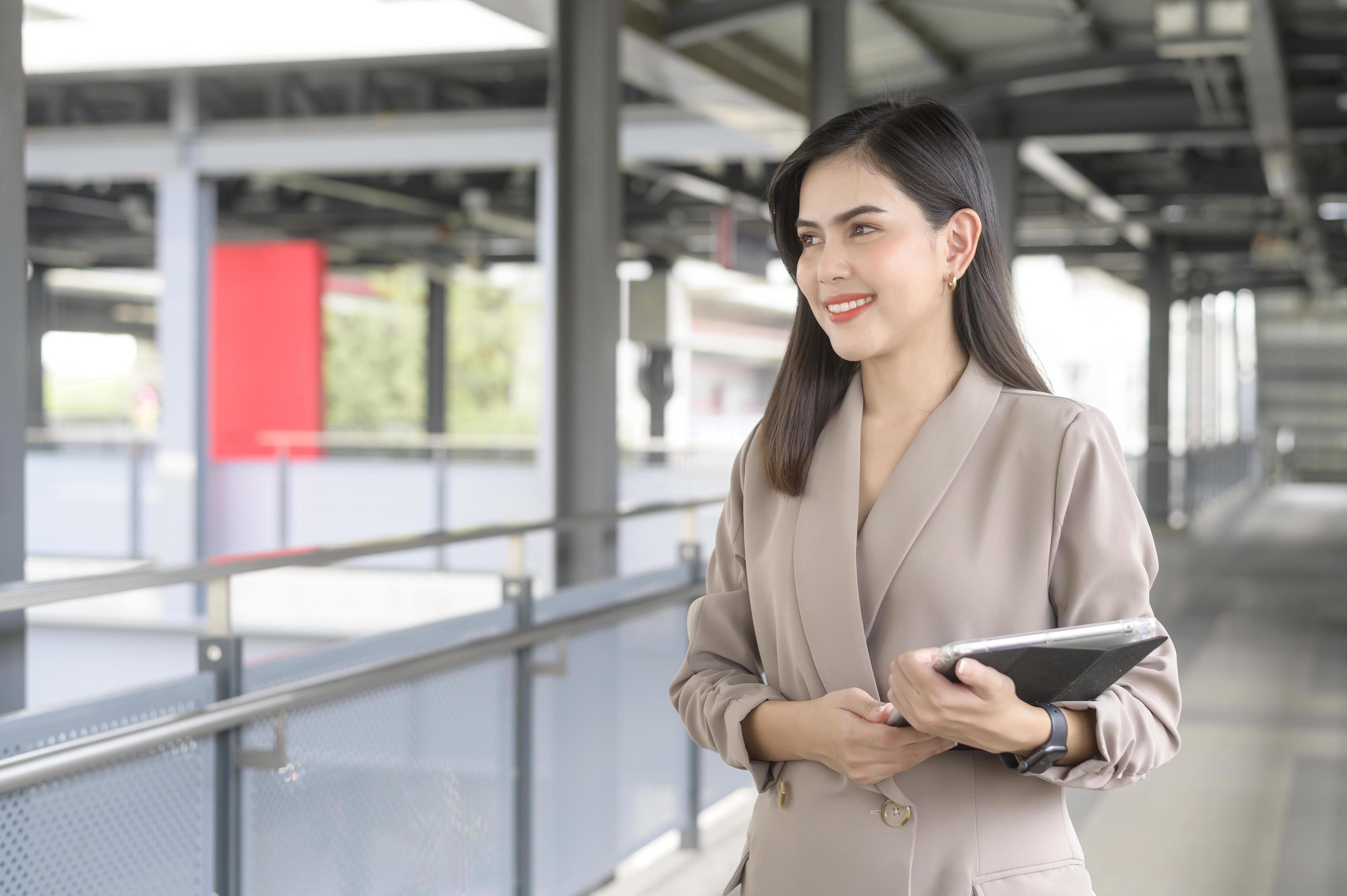 A young beautiful businesswoman is using tablet in Modern city , business technology , city lifestyle concept Stock Free