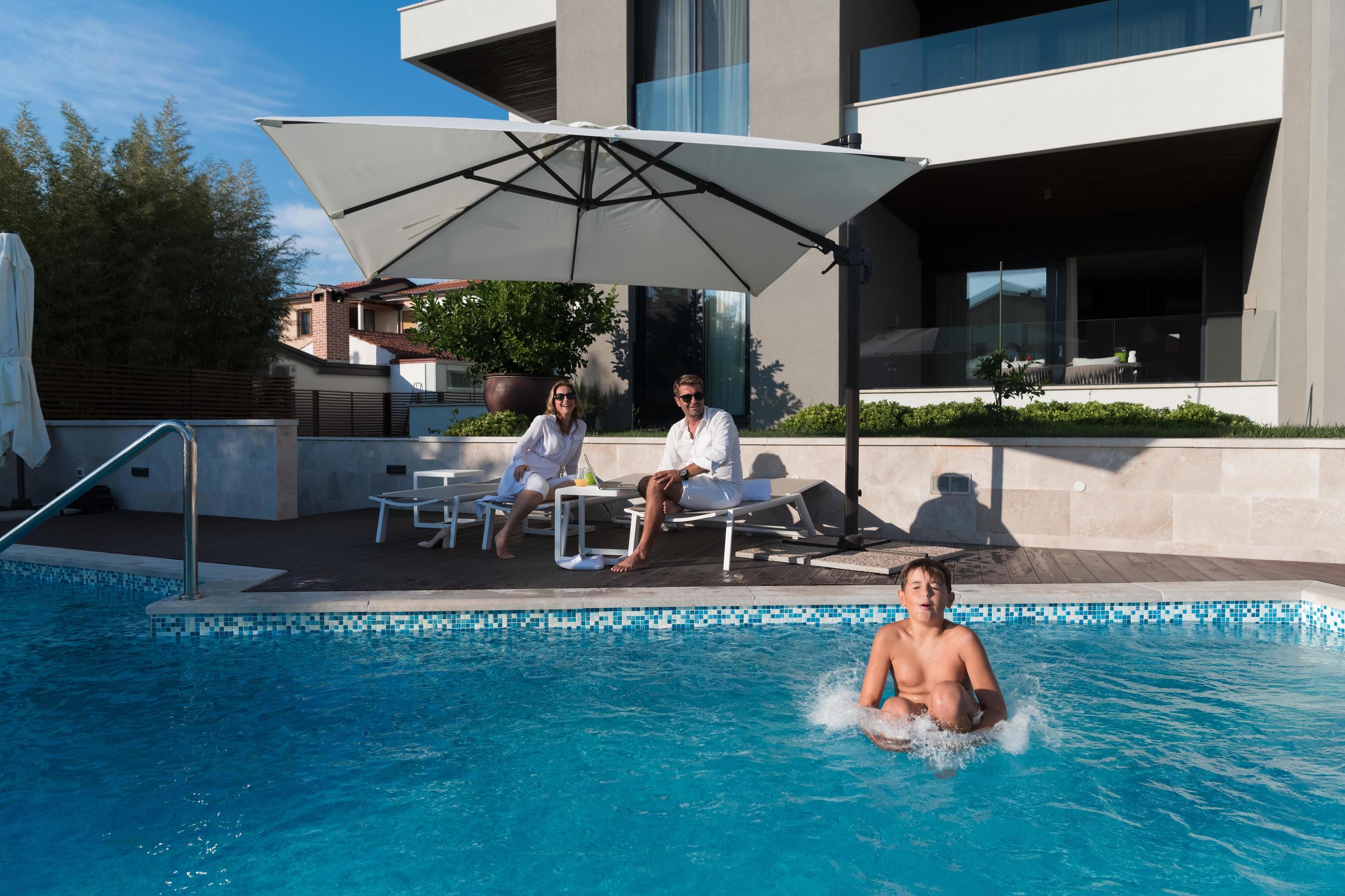 Happy family enjoys vacation in a luxury house with pool. Senior couple spends time with their son during the vacation. Selective focus Stock Free