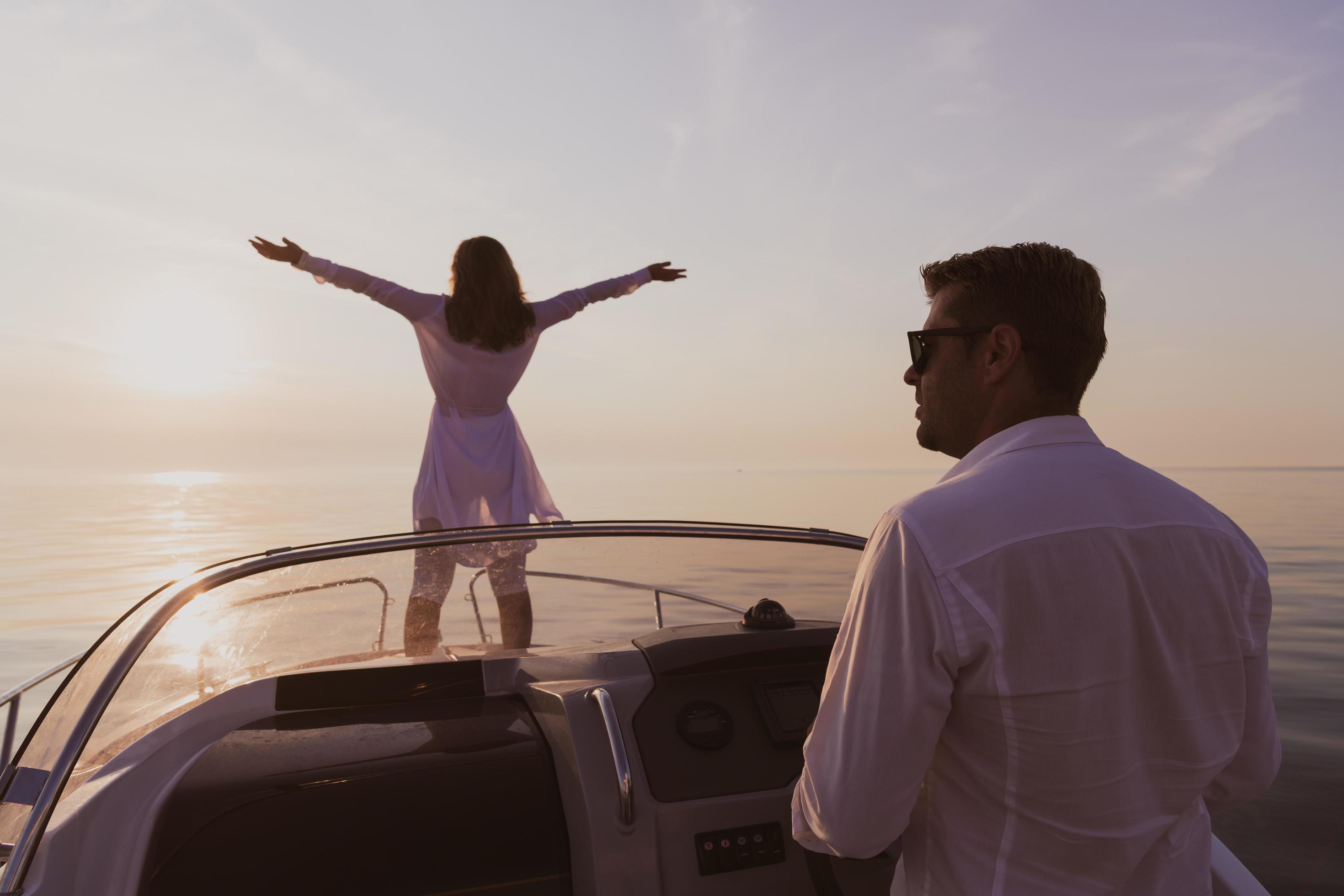 A senior couple in casual outfits with their son enjoy while riding a boat at sea at sunset. The concept of a happy family. Selective focus Stock Free