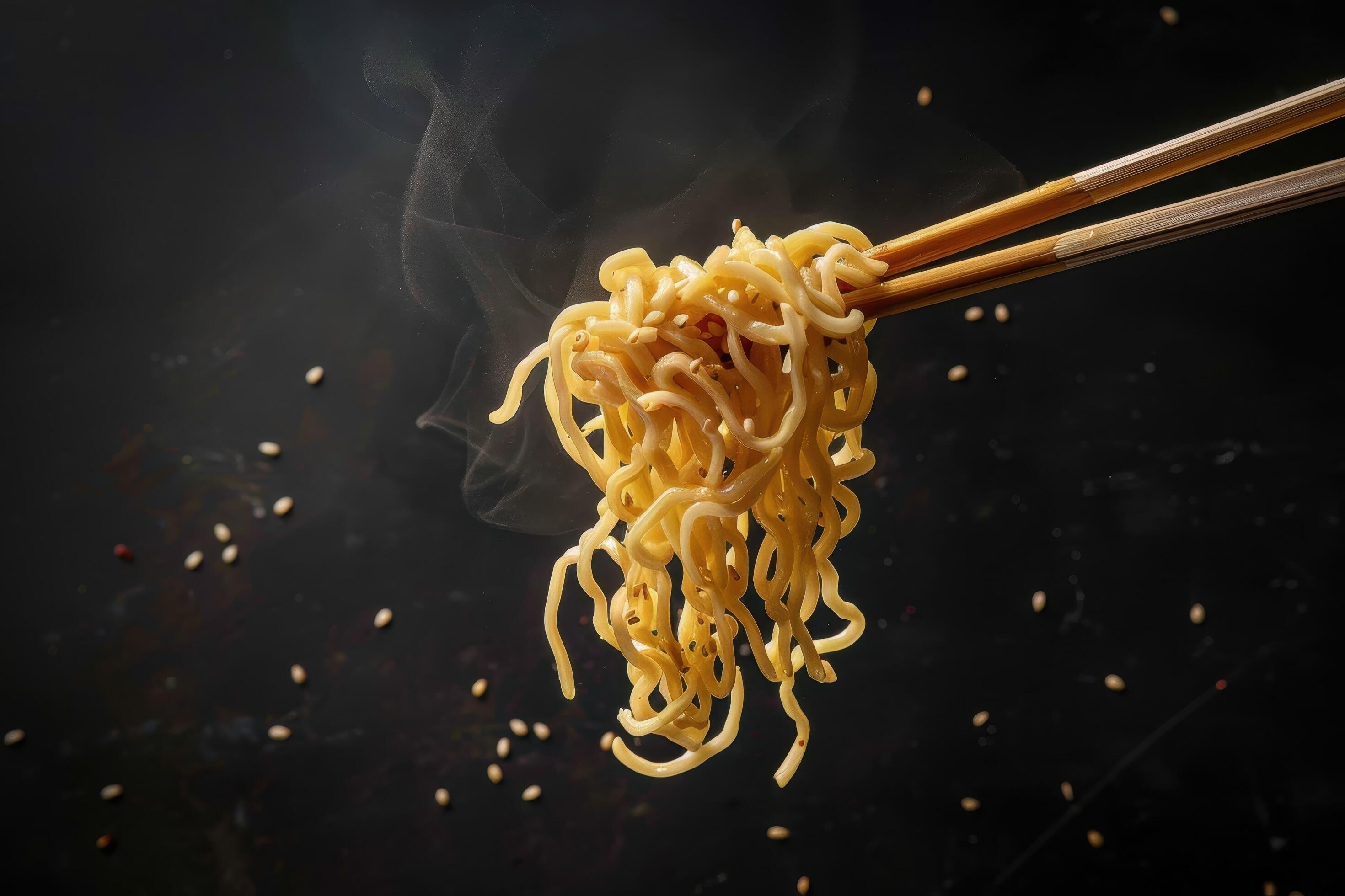 Steaming Noodles Held by Chopsticks Against a Black Background Stock Free