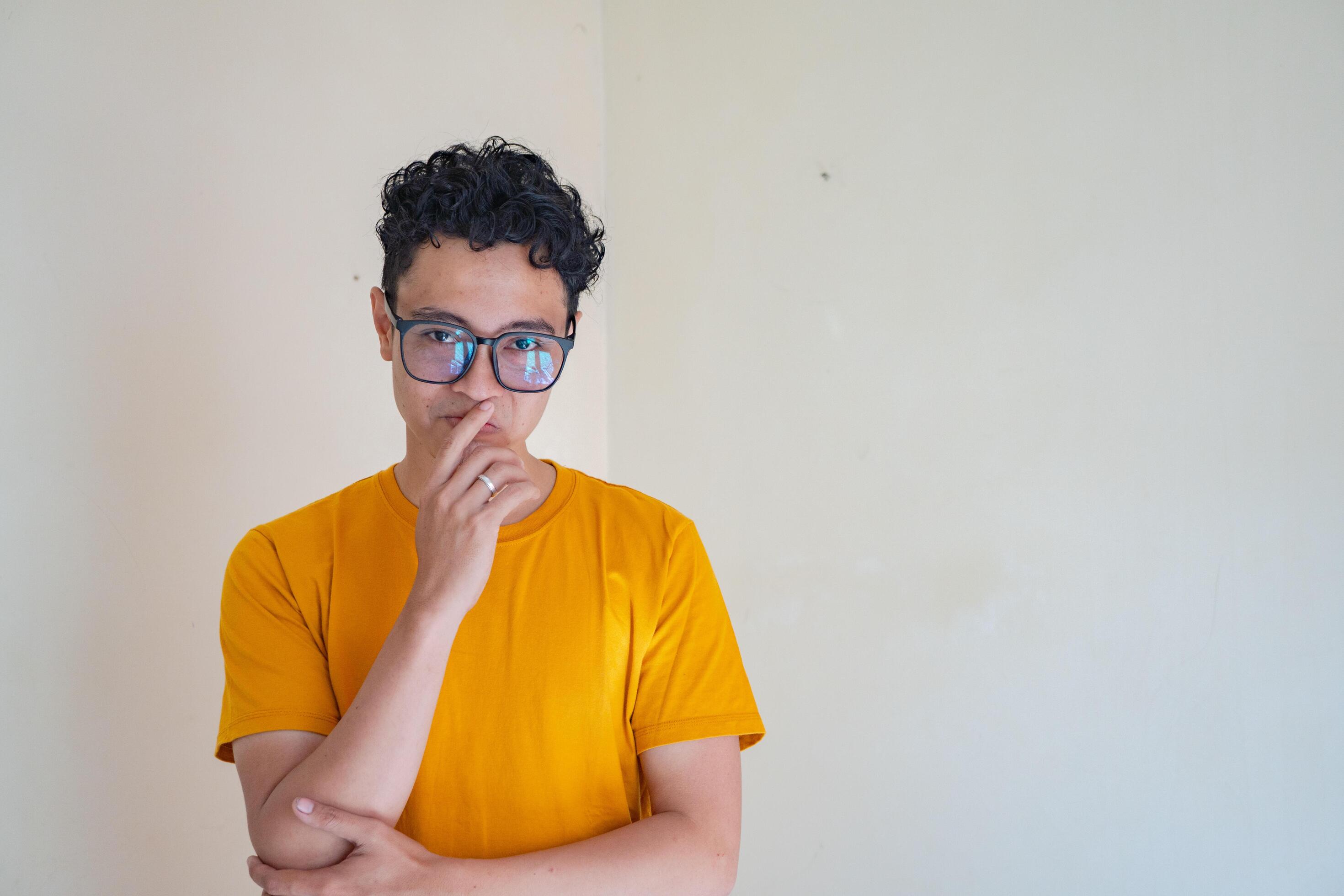 Young man wear yellow t-shirt with thinking pose expression gesture. The photo is suitable to use for man expression advertising and fashion life style. Stock Free