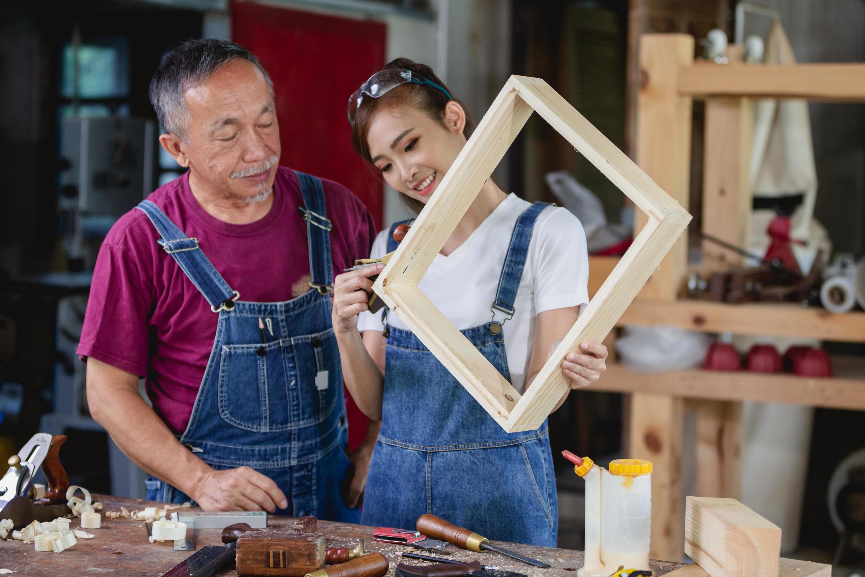 A carpenter woman and man works in her own woodworking shop. Carpenter work on wood plank in workshop. small business concep Stock Free