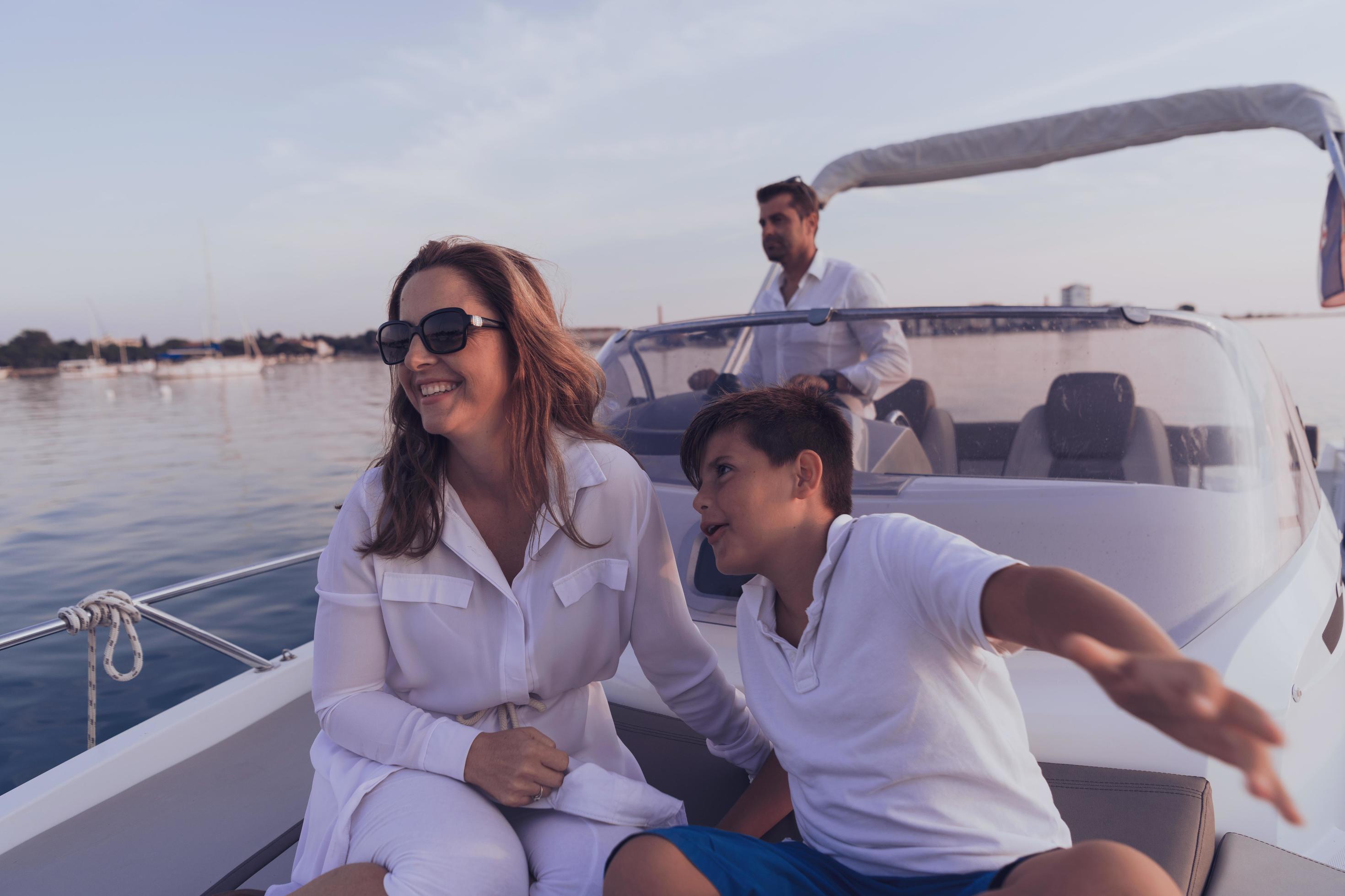 A senior couple in casual outfits with their son enjoy while riding a boat at sea at sunset. The concept of a happy family. Selective focus Stock Free