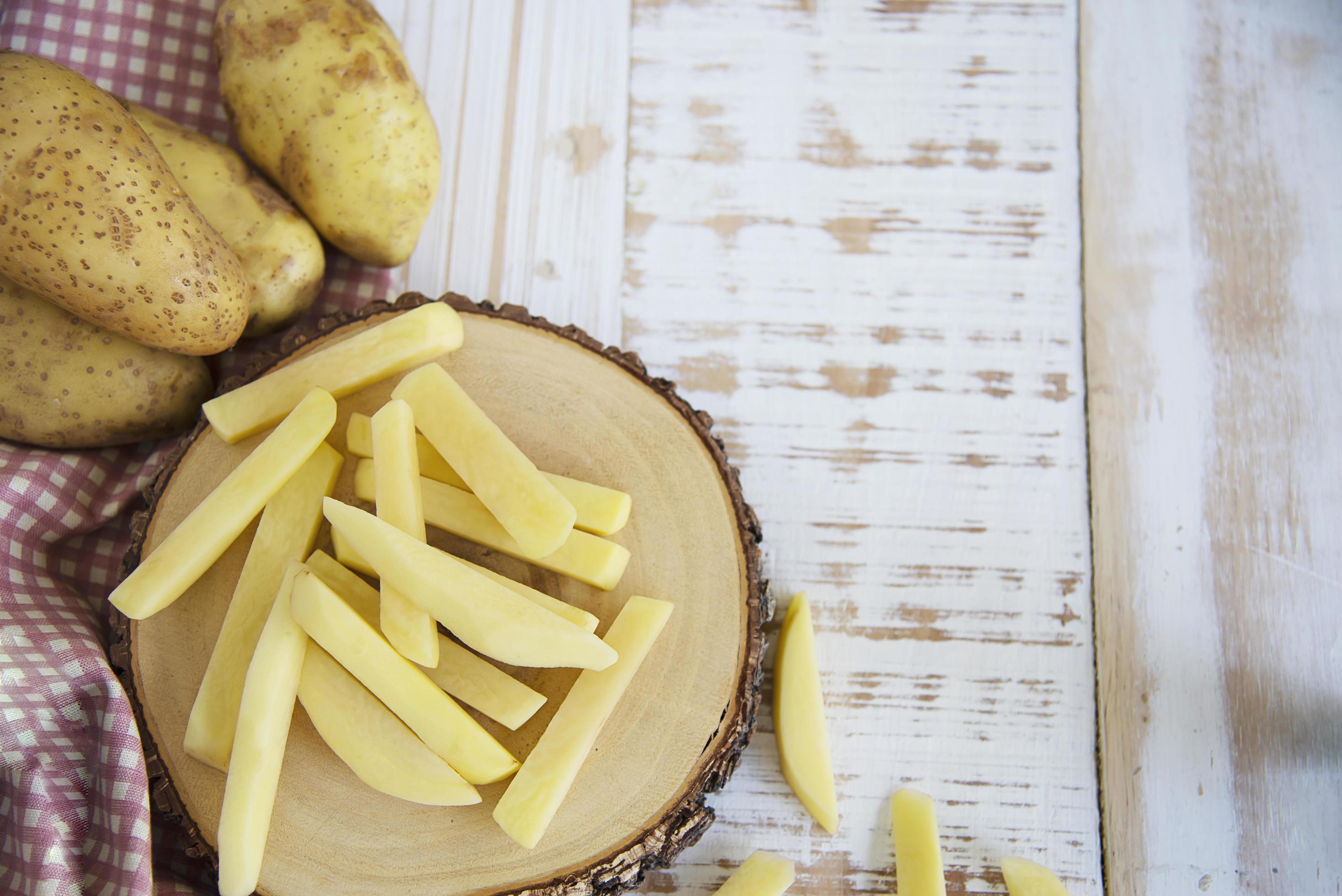 Sliced potato stick ready for making French fries – traditional food preparation concept Stock Free