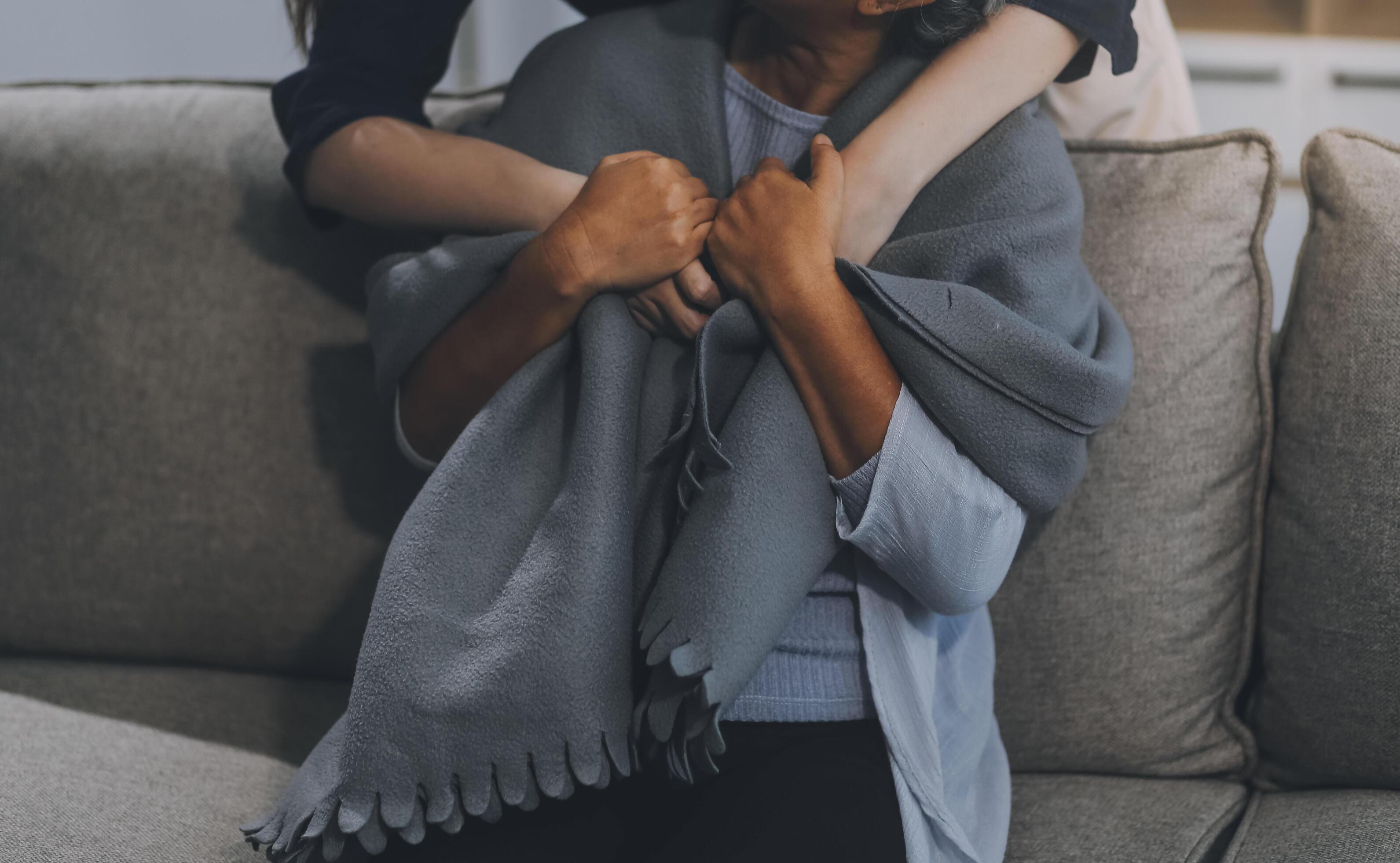 happy family Granddaughter takes care of her grandmother with warm cloths sitting on the sofa. Stock Free