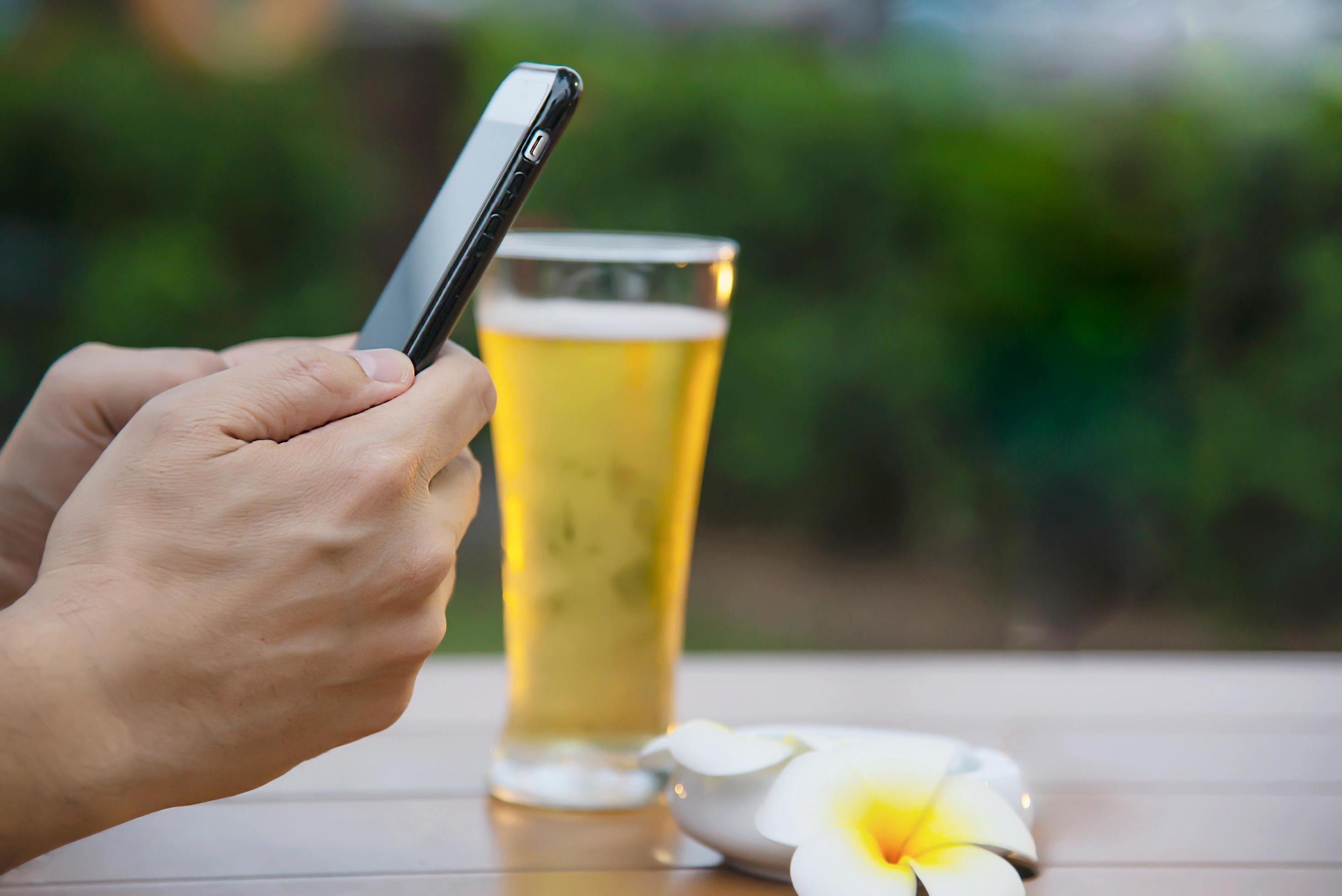 Man using mobile during happy time relax in restaurant with softdrink and green garden background – people relax with technology lifestyle concept Stock Free