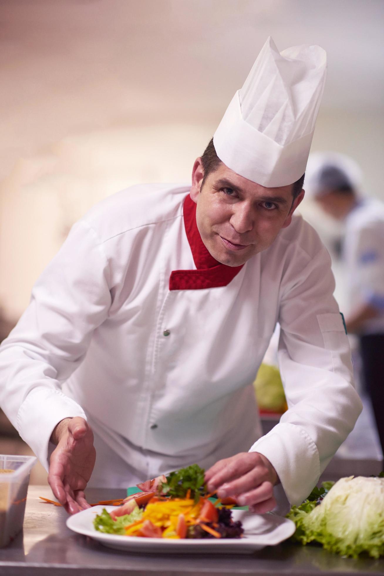 chef in hotel kitchen preparing and decorating food Stock Free