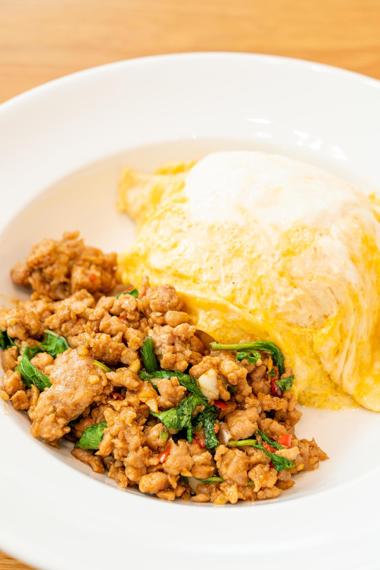 Stir-fried pork and basil with creamy omelet on rice – Asian food style Stock Free