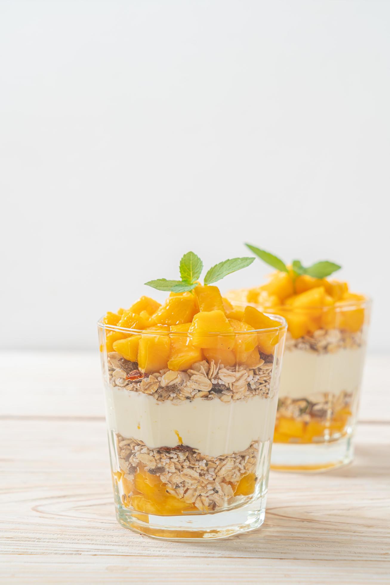 Fresh mango yogurt with granola in glass – healthy food style Stock Free