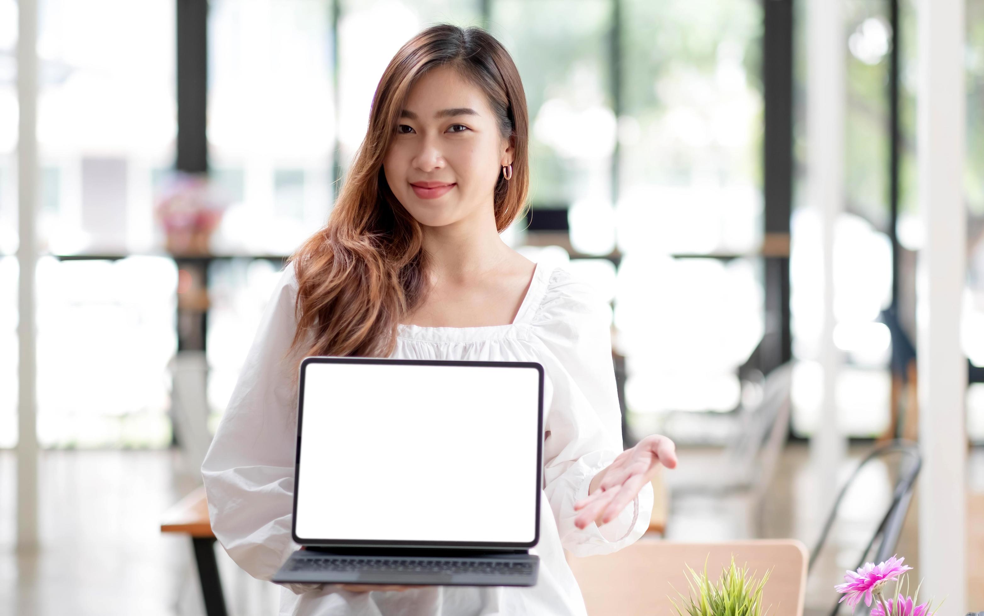 Happy young asian woman clothes on white background. People lifestyle concept. Mock up copy space. Hold laptop pc computer with blank empty screen Stock Free