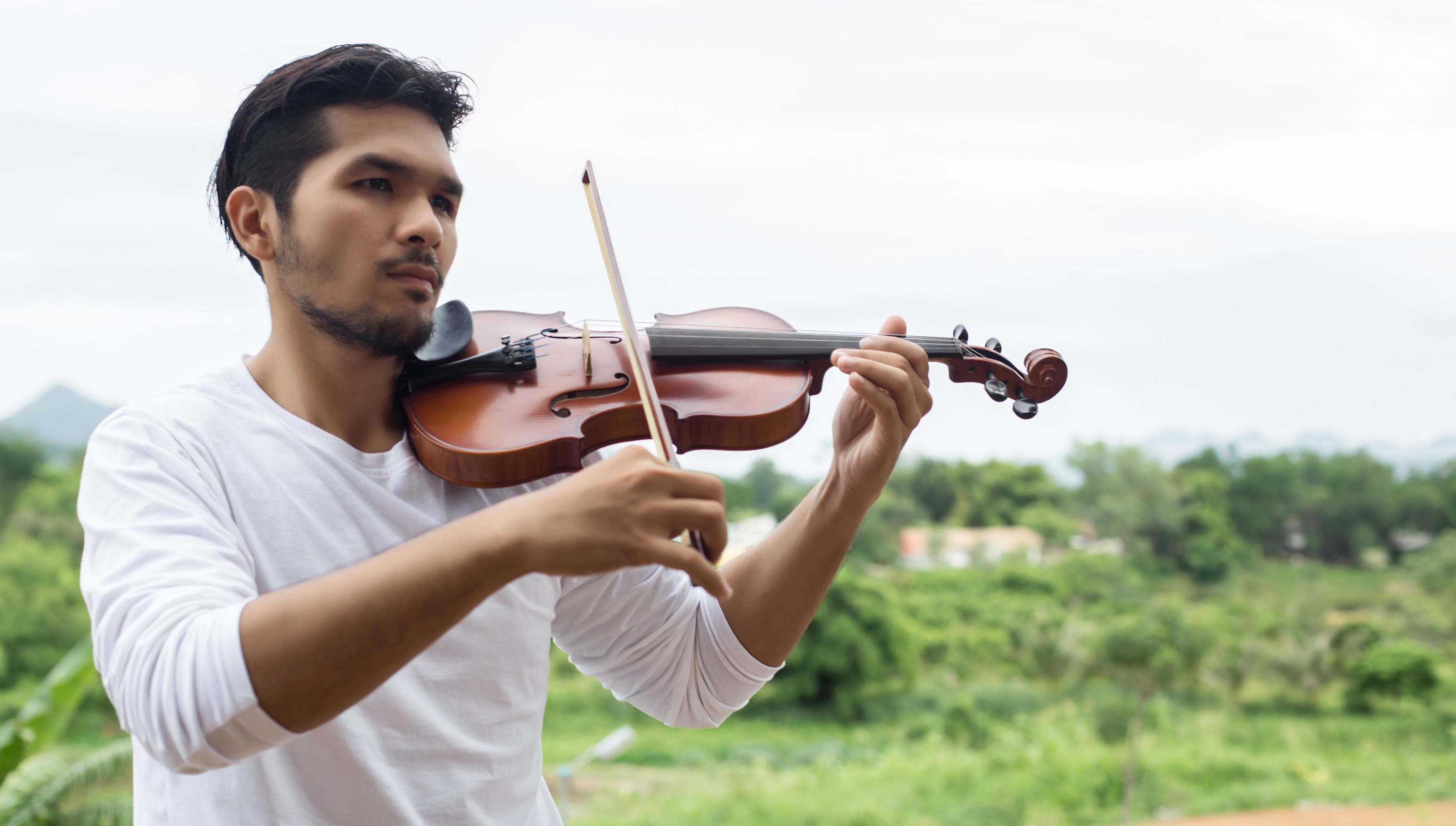 Young hipster musician man playing violin in the nature outdoor lifestyle behind mountain. Stock Free