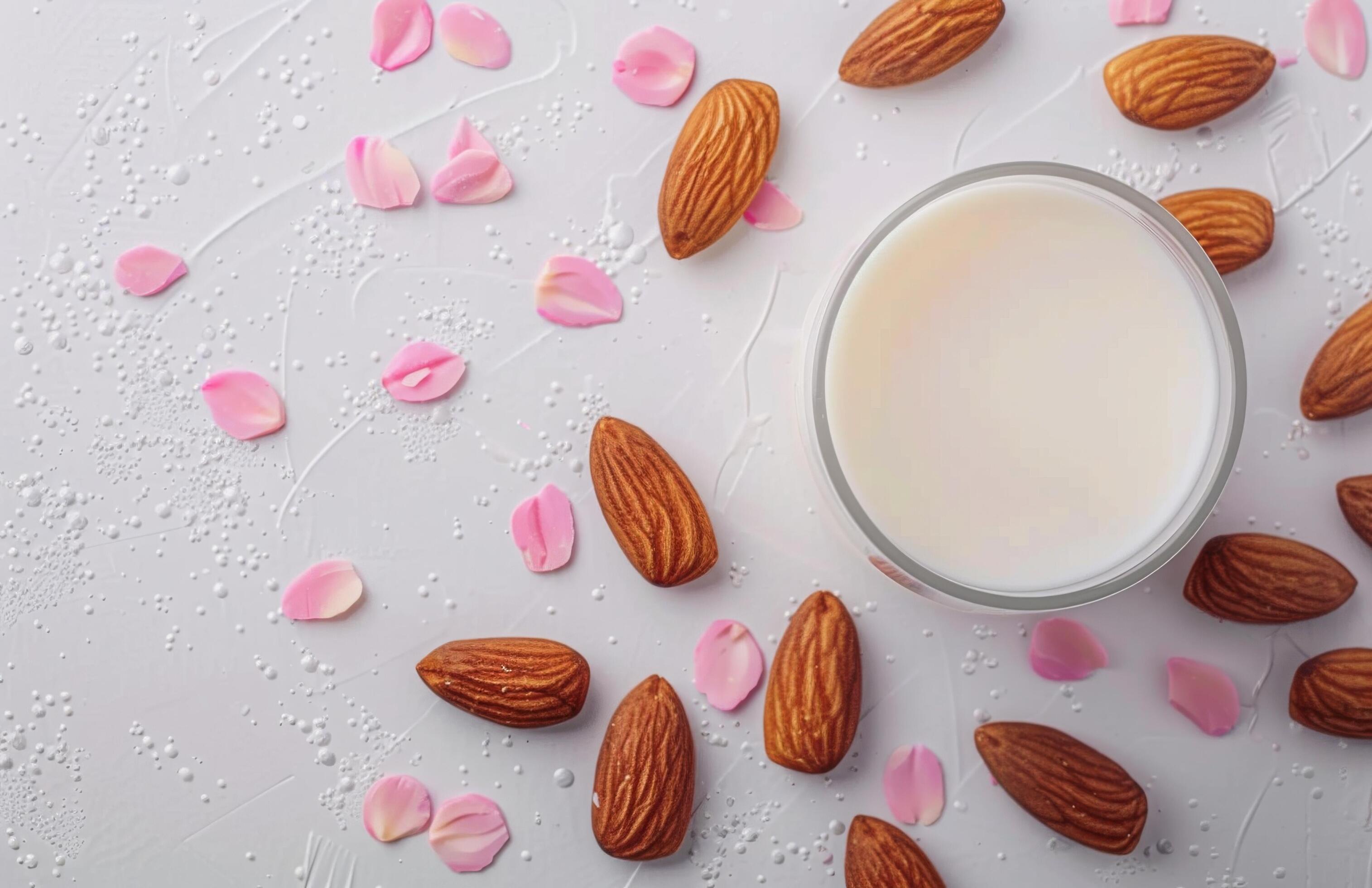 Creamy Almond Milk Surrounded by Almonds and Fresh Leaves on a White Background Stock Free