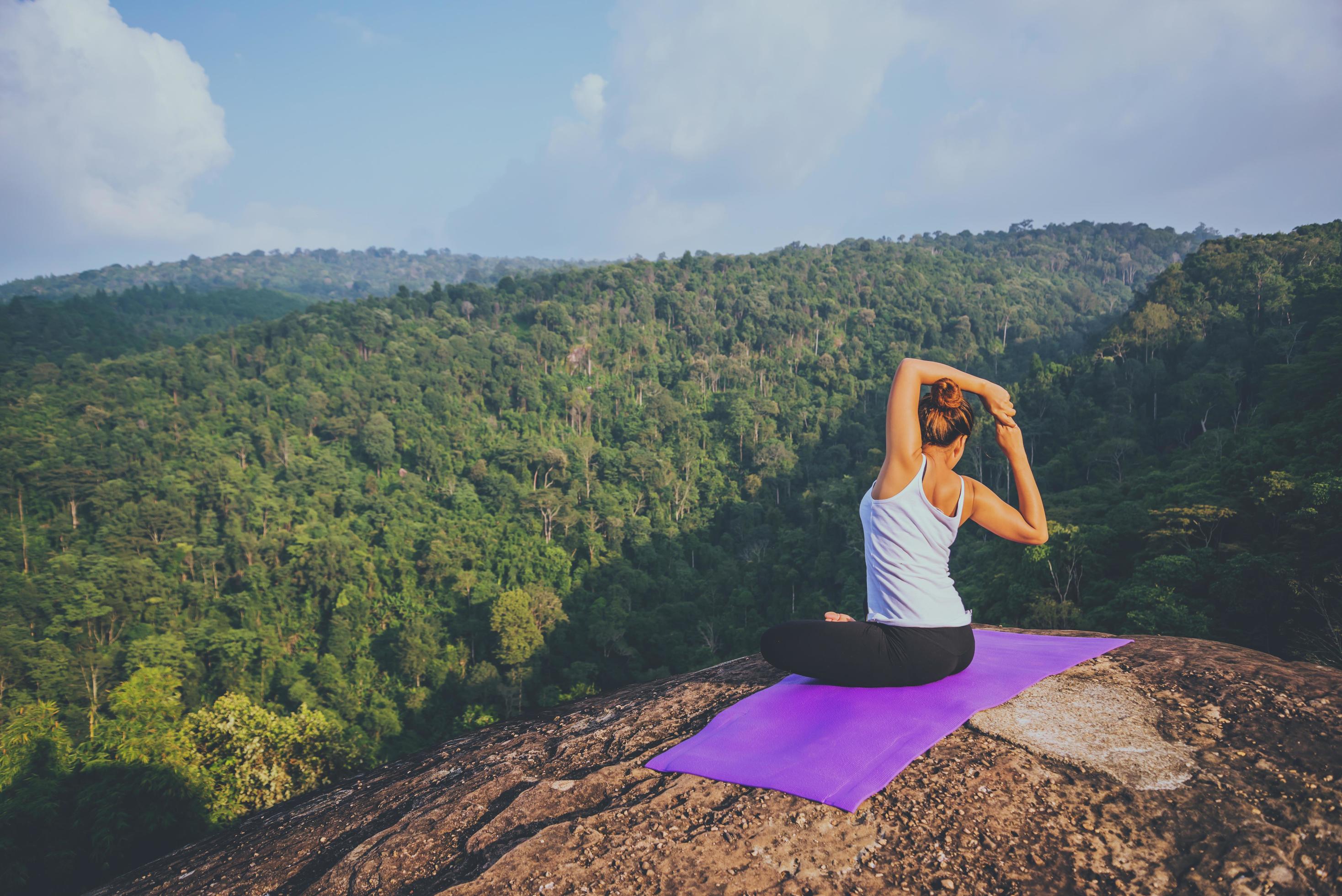 Asian women relax in the holiday. Play if yoga. On the Moutain rock cliff. Nature of mountain forests in Thailand Stock Free