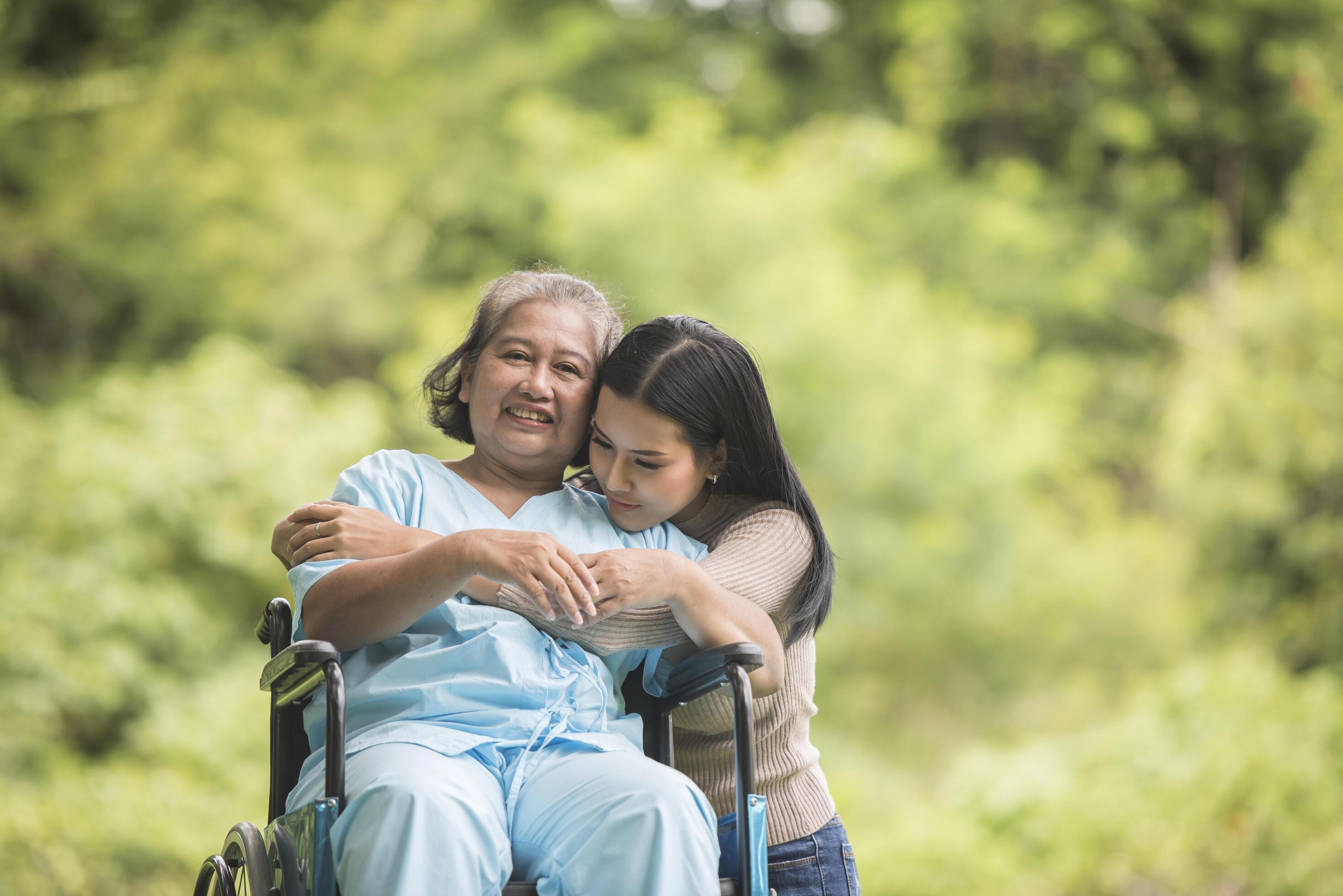 Granddaughter talking with her grandmother sitting on wheelchair, cheerful concept, happy family Stock Free