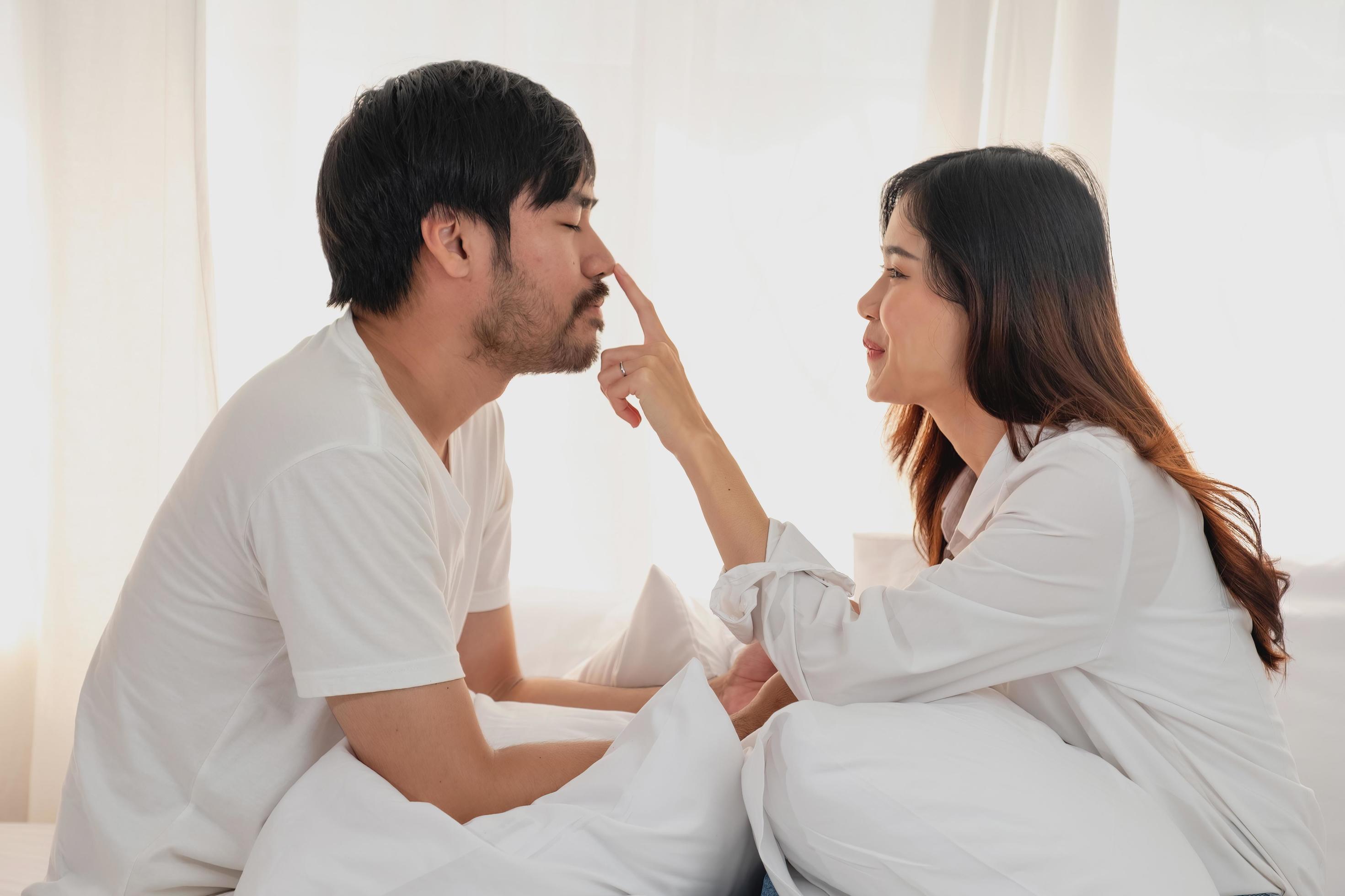 Happy young asian couple embracing, teasing, playing cheerfully in bed at home, romantic time to enhance family bonding. family concept. Stock Free