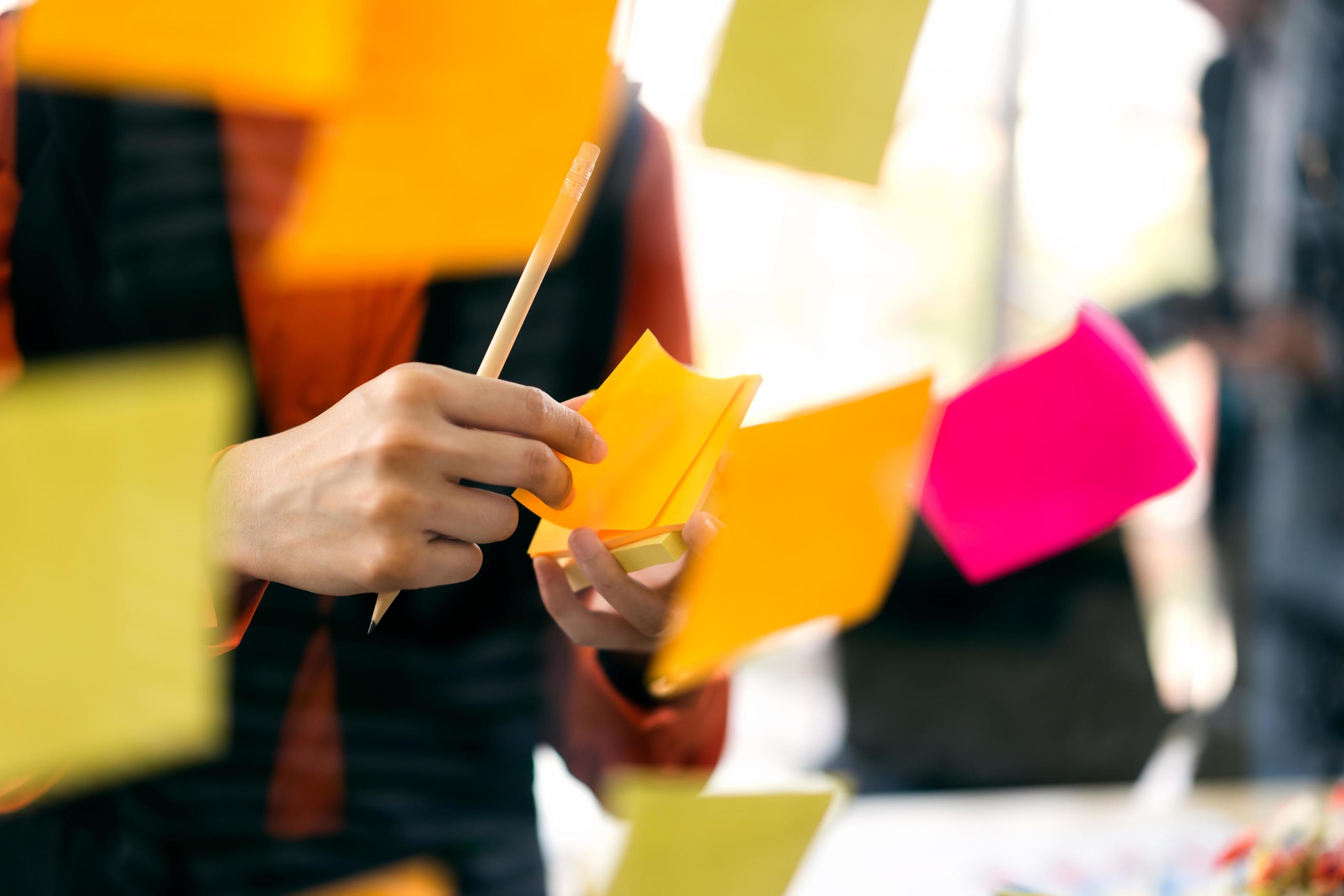 Adult business woman use a post it for stick on a glass board. Stock Free