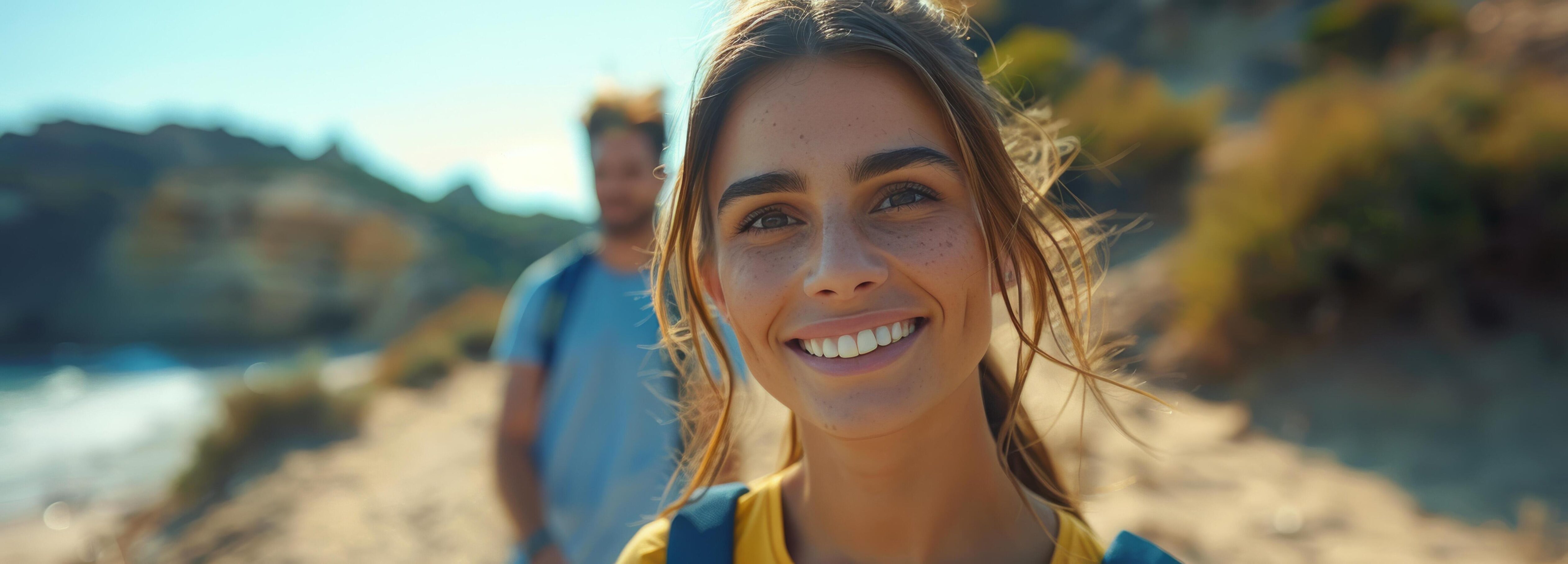 Young Woman Smiling Brightly on Beach With Friend in Background Stock Free