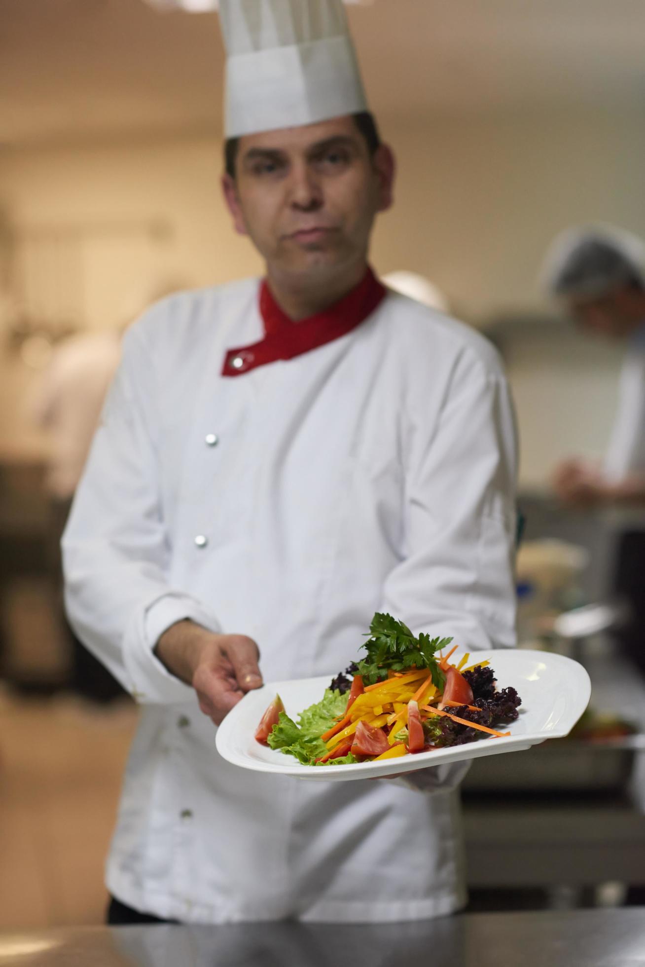 chef in hotel kitchen preparing and decorating food Stock Free