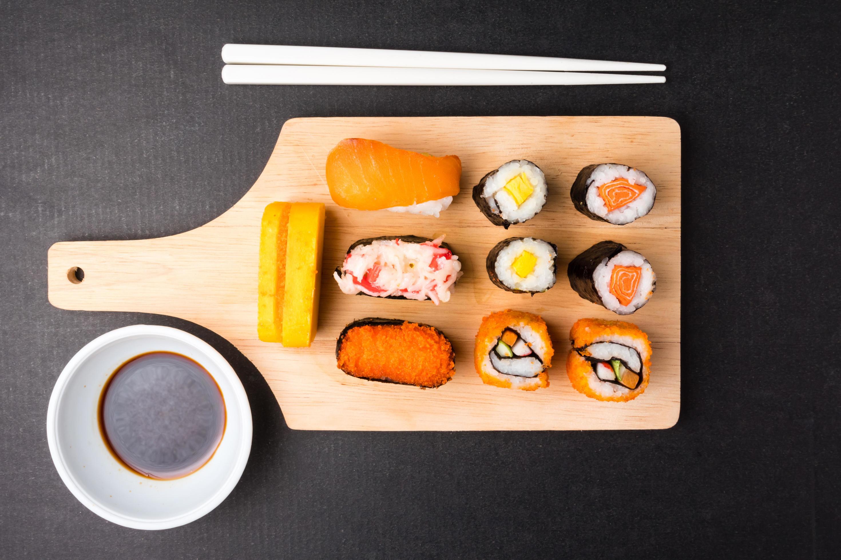 Top view of Sushi set on wooden tray with chopsticks and sauce on black background, Japanese food. Stock Free