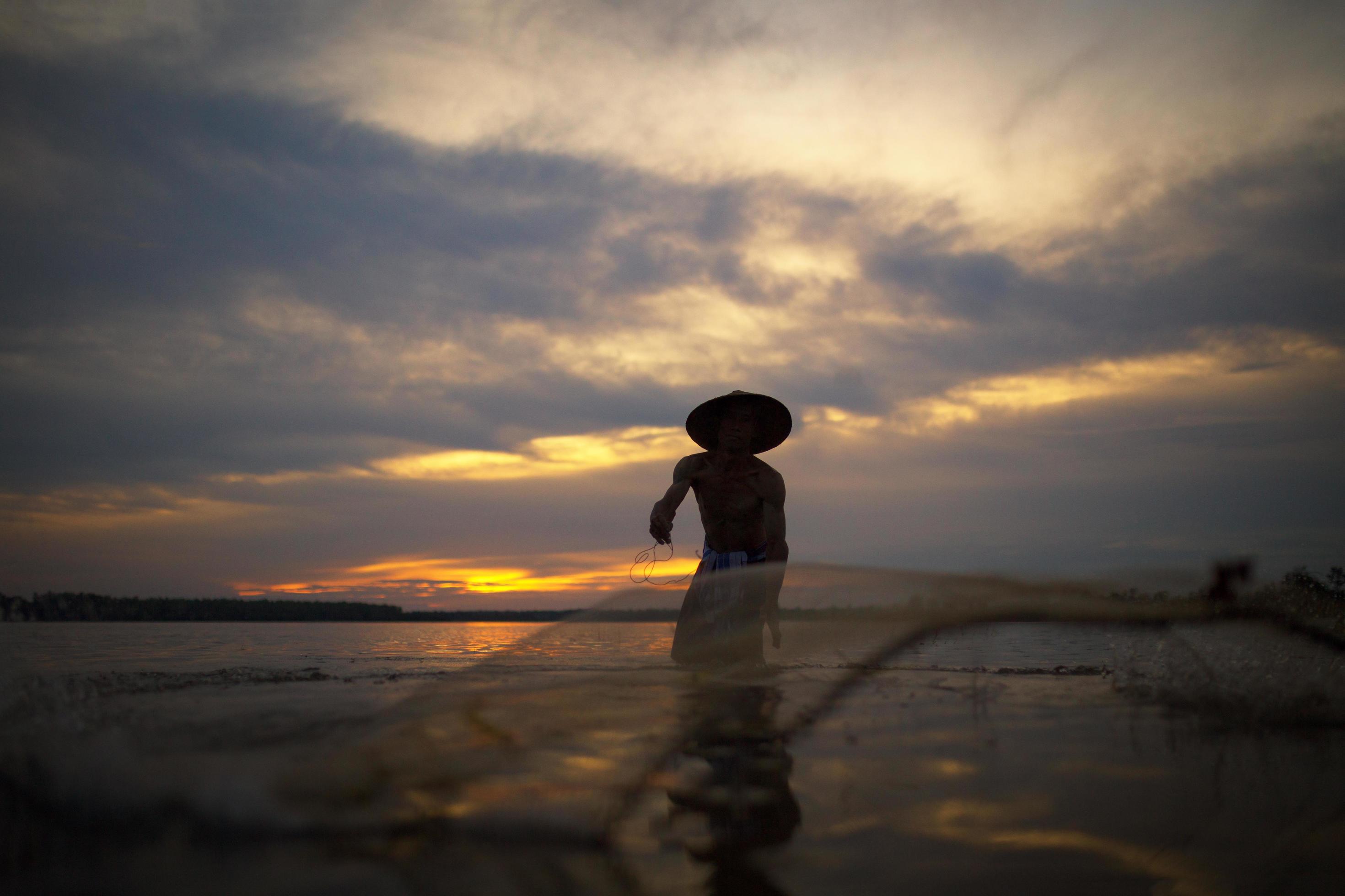 Lifestyles of fishermen are netting to catch fish in the lake on sunset Stock Free