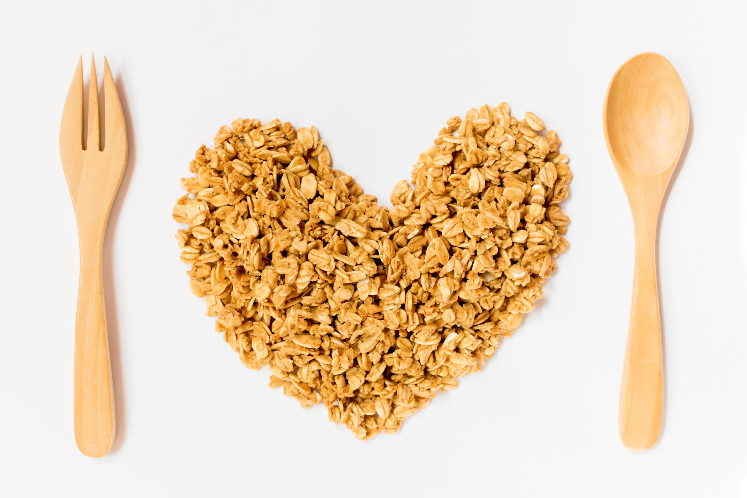 Close up of uncooked rolled oats shape form heart with wooden spoon and fork isolated on white background. food ,Raw food ,Valentine day. Stock Free