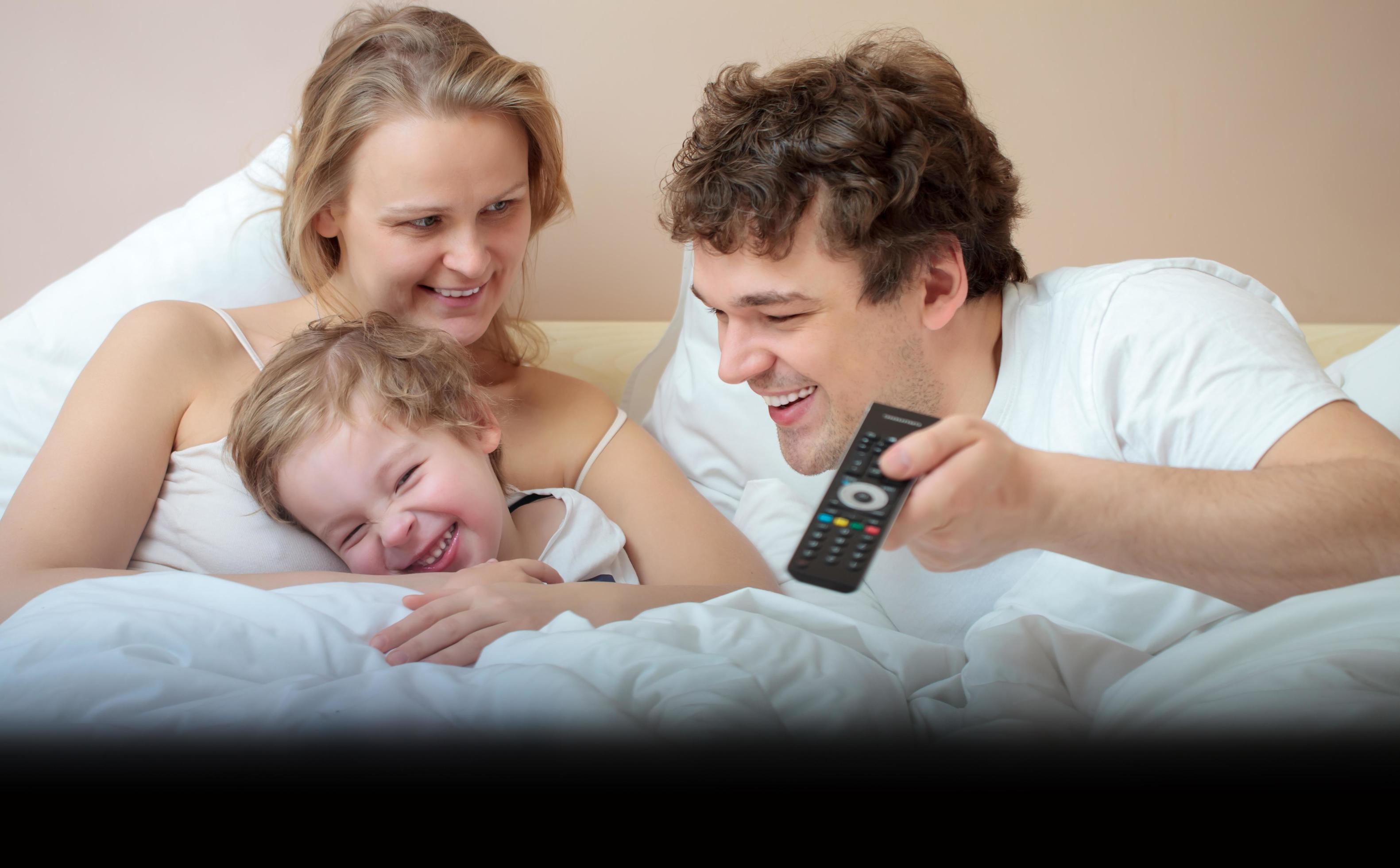 Family lying in bed watching television Stock Free