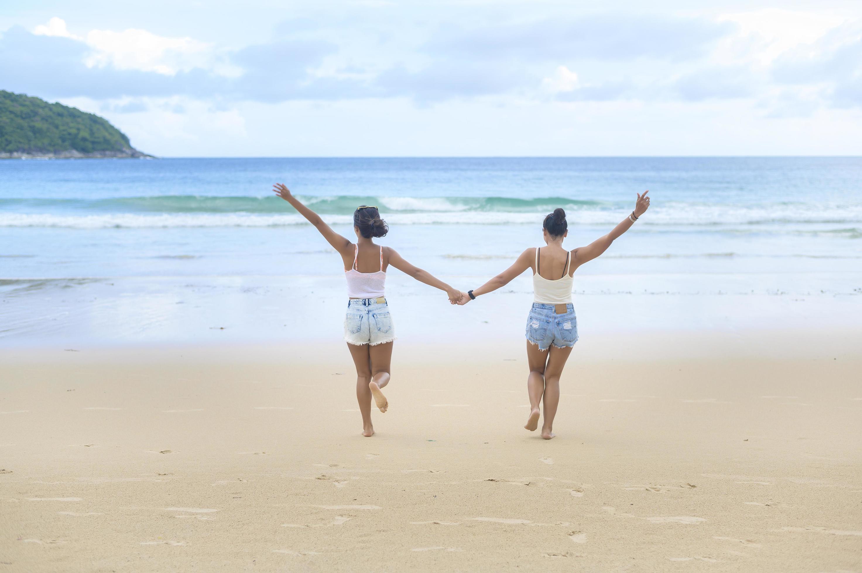 Two attractive women friends enjoying and relaxing on the beach, Summer, vacation, holidays, Lifestyles concept. Stock Free