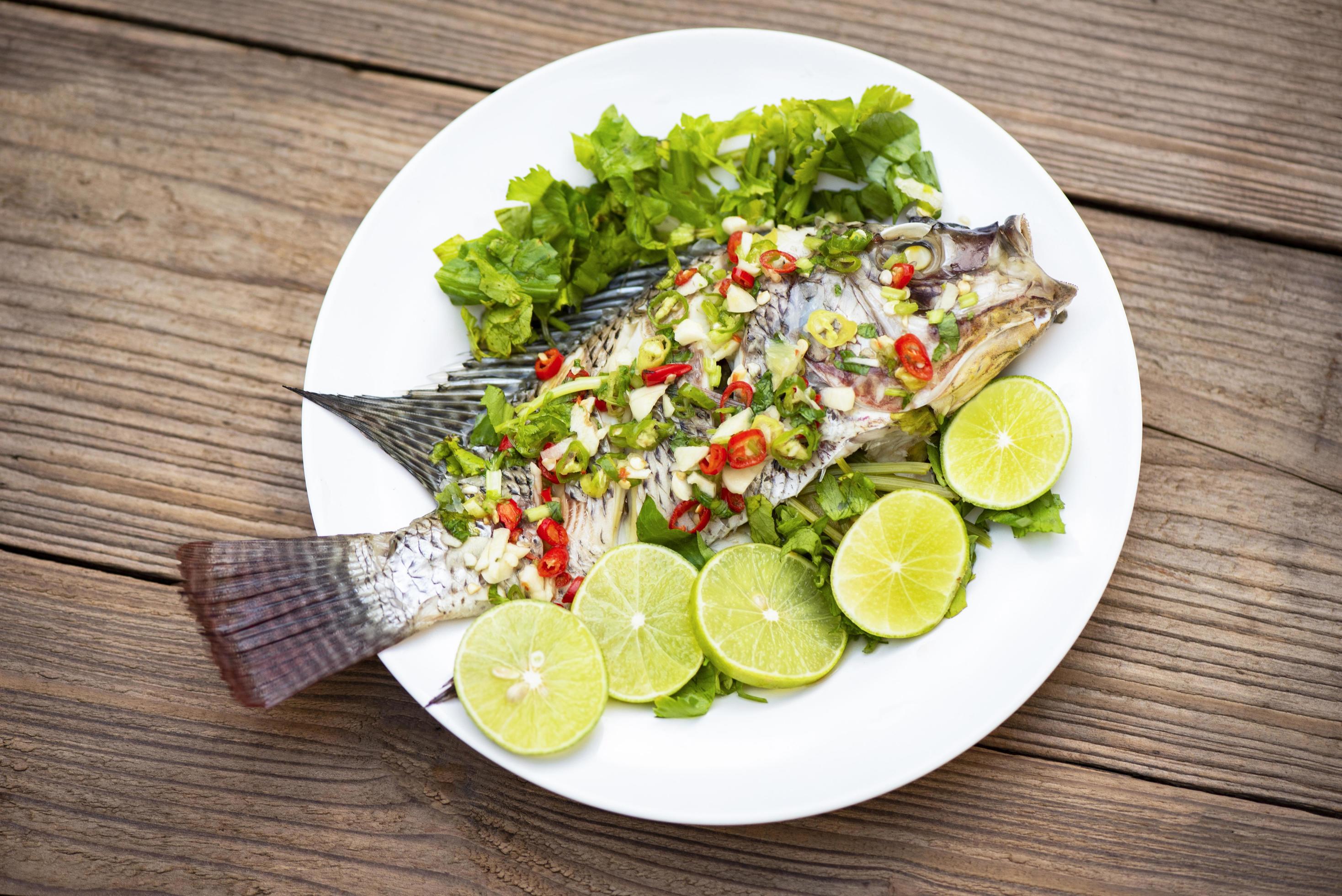 Steamed tilapia fish with chili and lime lemon sauce with herb and Vegetable on plate, Fish steam lime – Thai food Stock Free