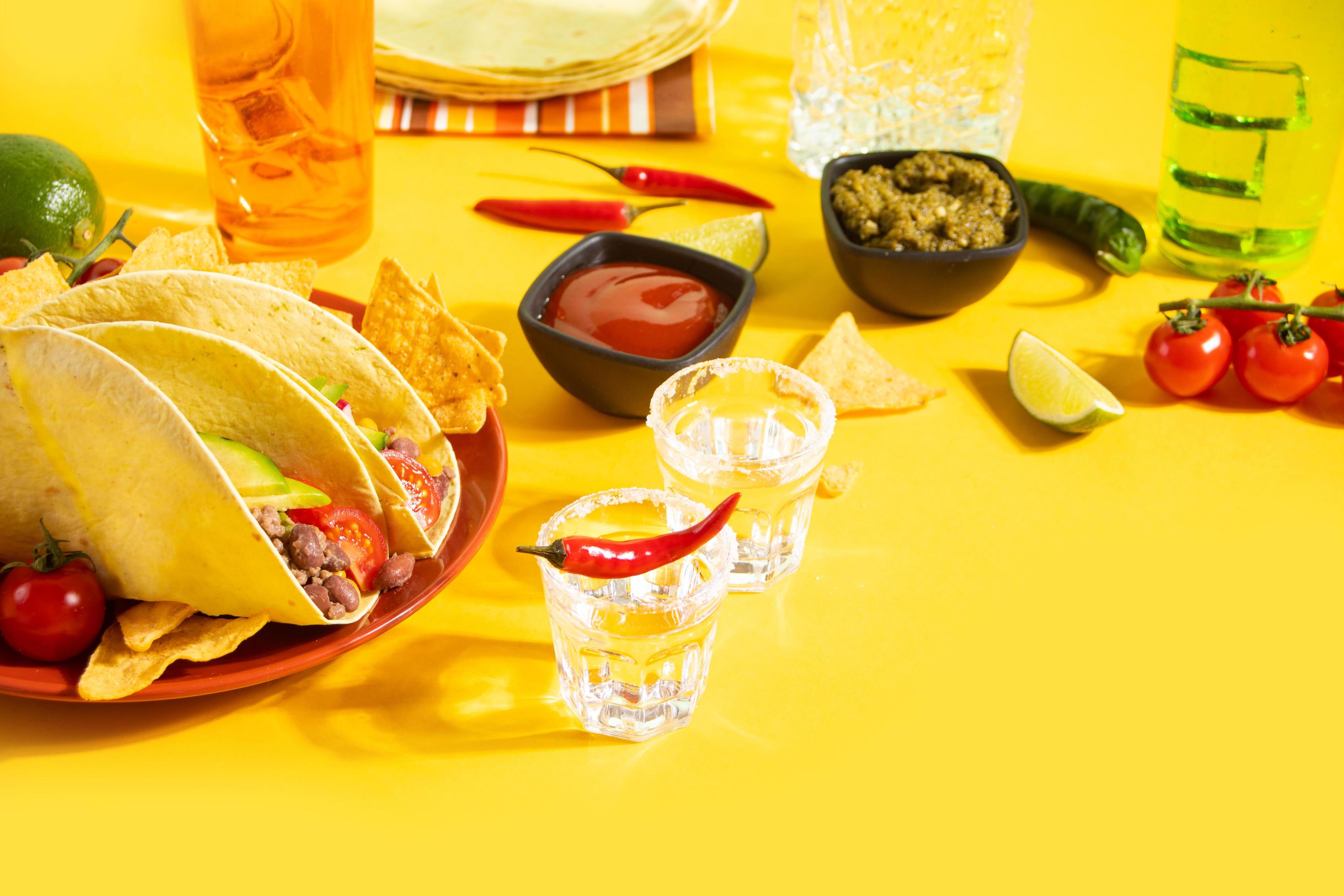 Mexican tequila shots with lime and hot red chili with traditional food corn tacos on the background Stock Free