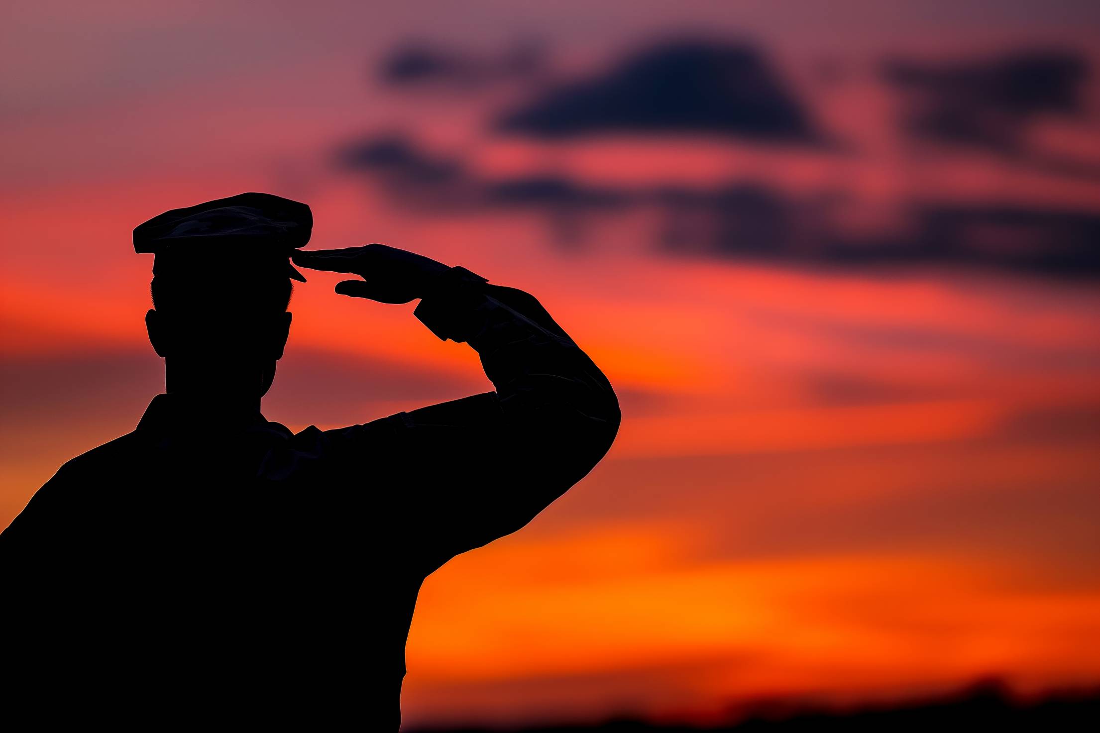 Silhouette of a Soldier Saluting at Red Sky Stock Free