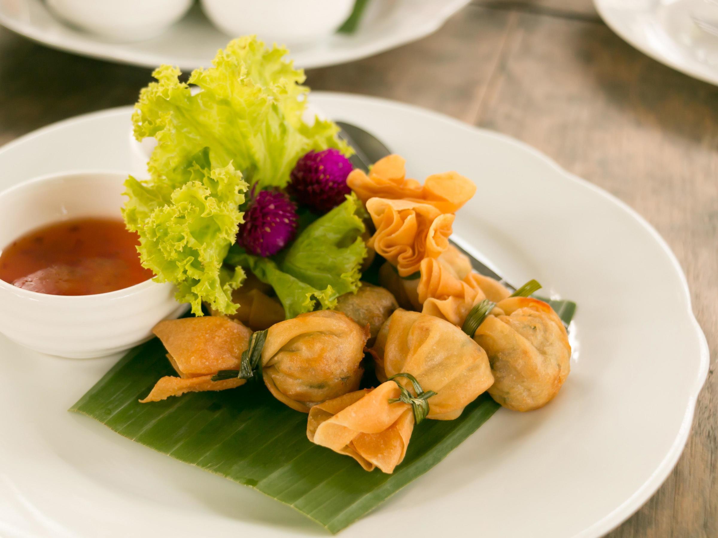 The ancient Thai snack named Thung Thong with beautiful food decorated served on white plate with sweet sauce. Stock Free