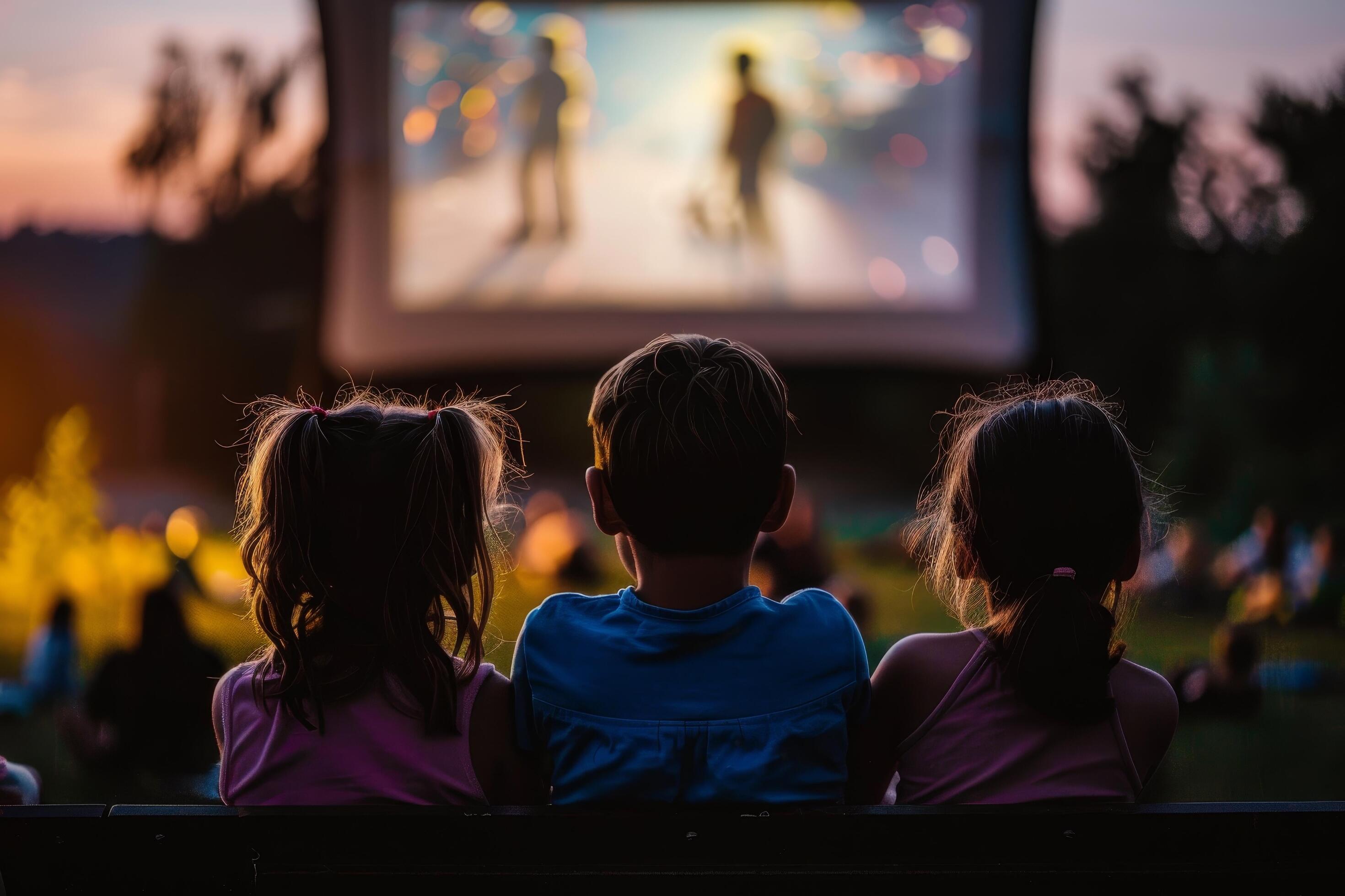 people are sitting in lawn chairs in front of a large screen Stock Free