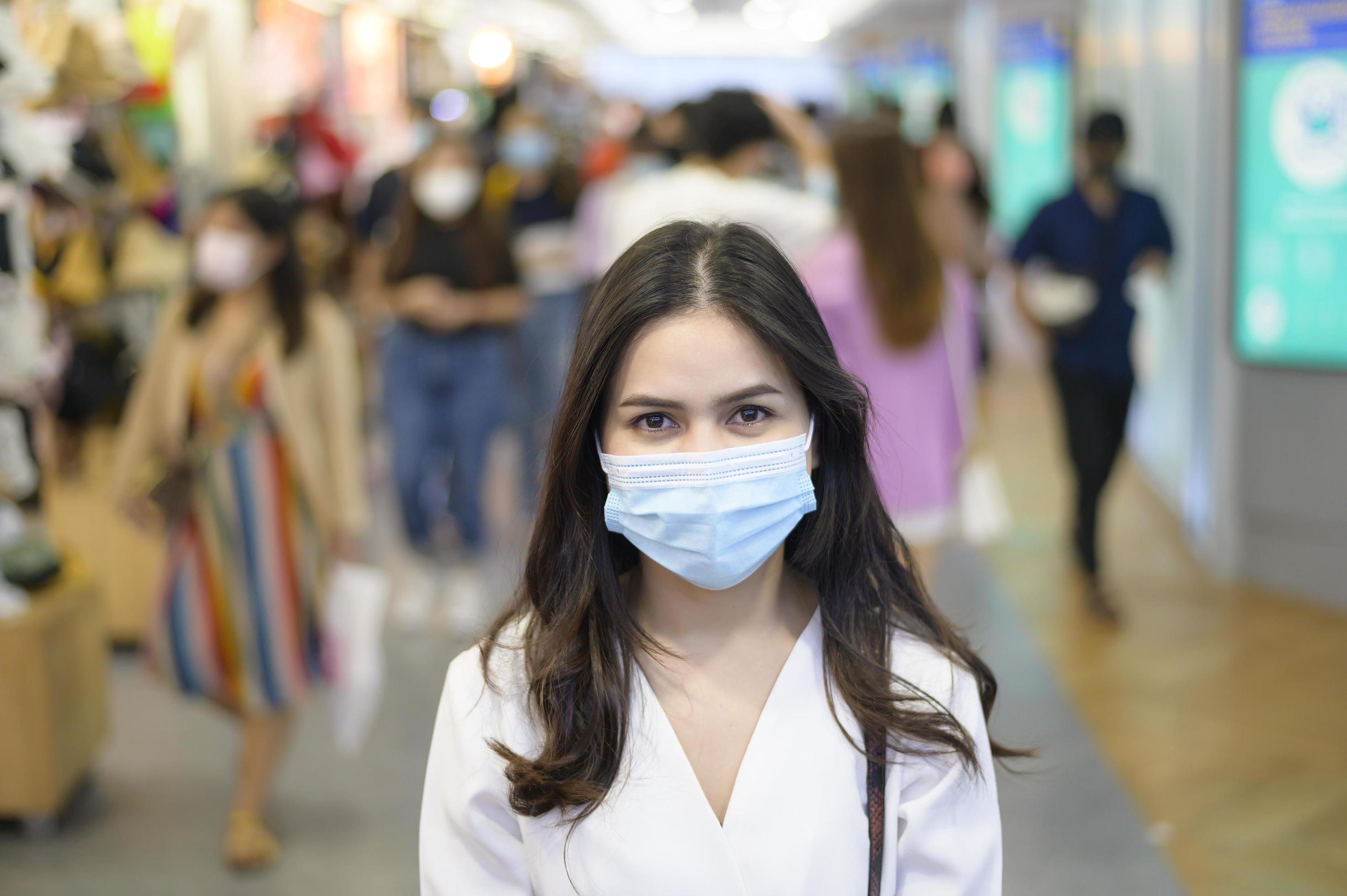 A woman is wearing protective mask on Street with Crowded people while covid-19 pandemic, Coronavirus protection , safety lifestyles concept Stock Free