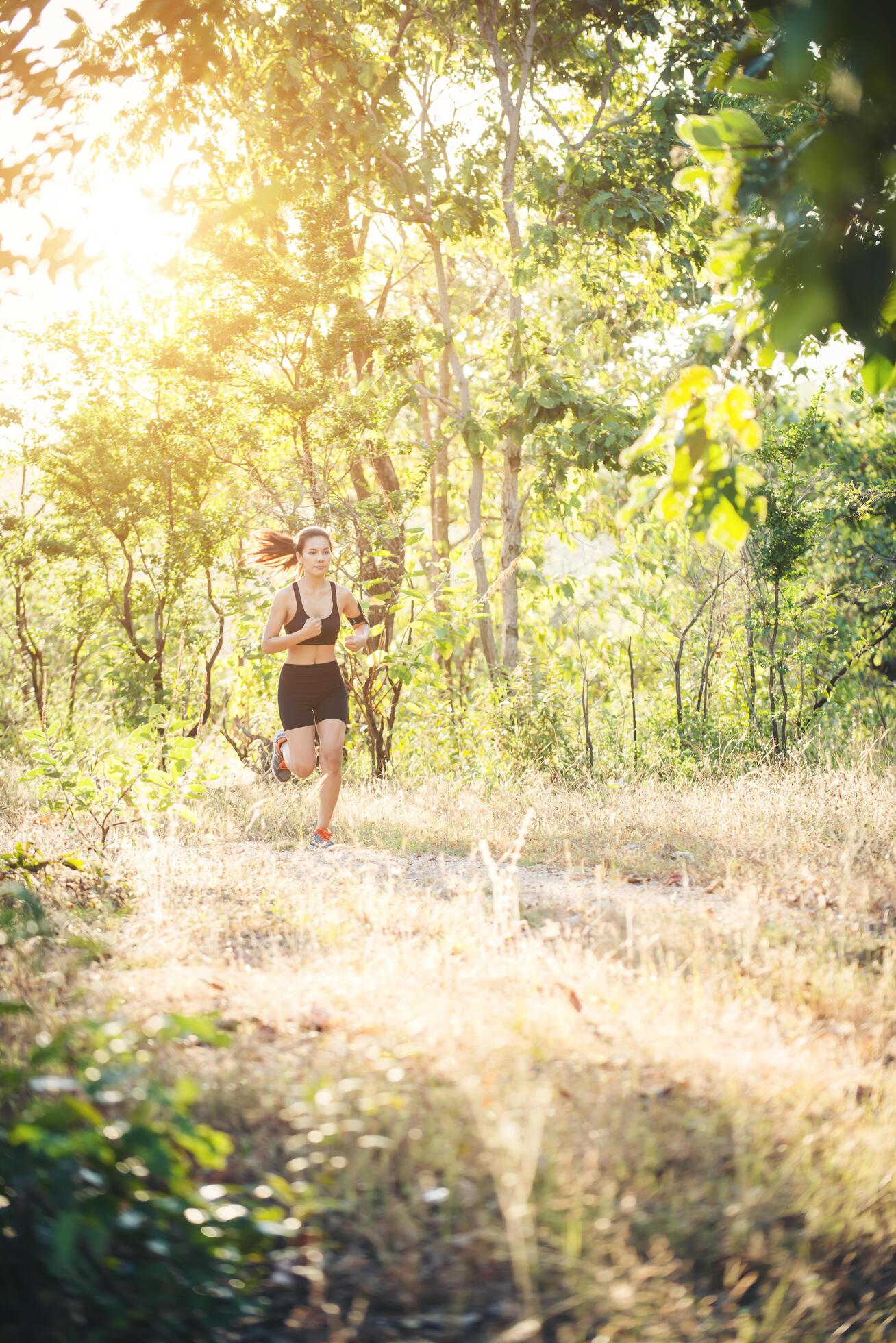 Young woman jogging on rural road in forest nature. Stock Free