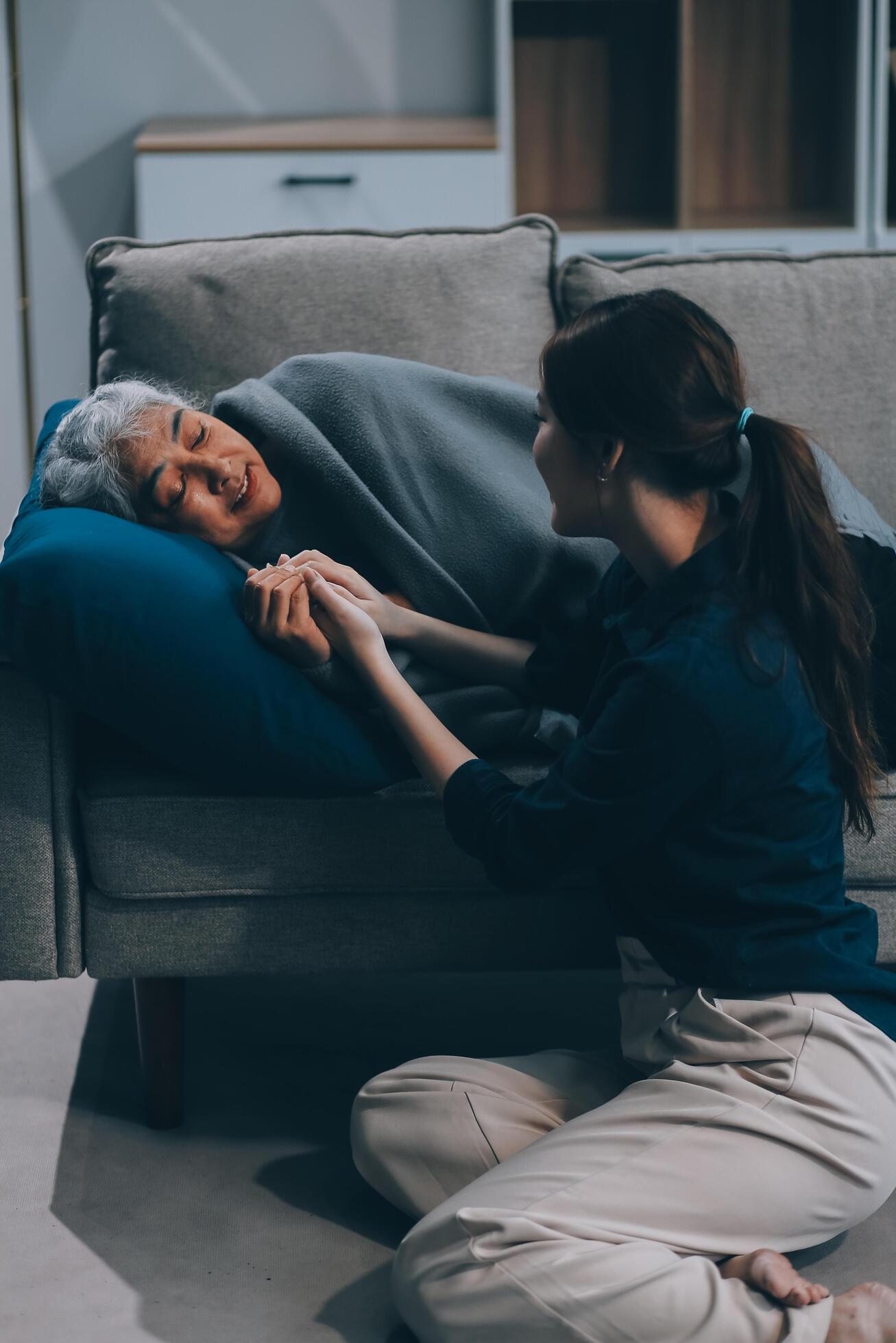 happy family Granddaughter takes care of her grandmother with warm cloths sitting on the sofa. Stock Free