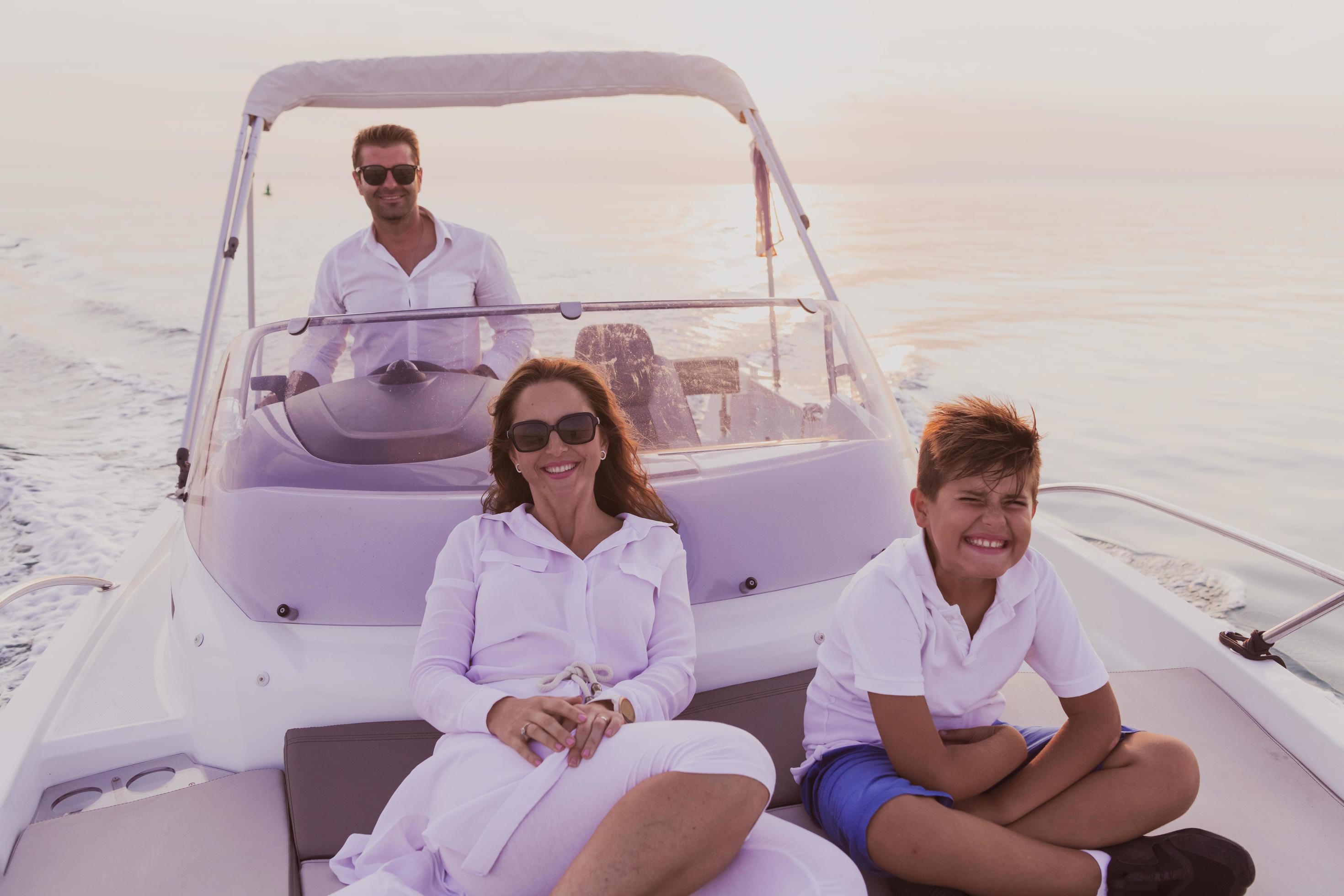 A senior couple in casual outfits with their son enjoy while riding a boat at sea at sunset. The concept of a happy family. Selective focus Stock Free