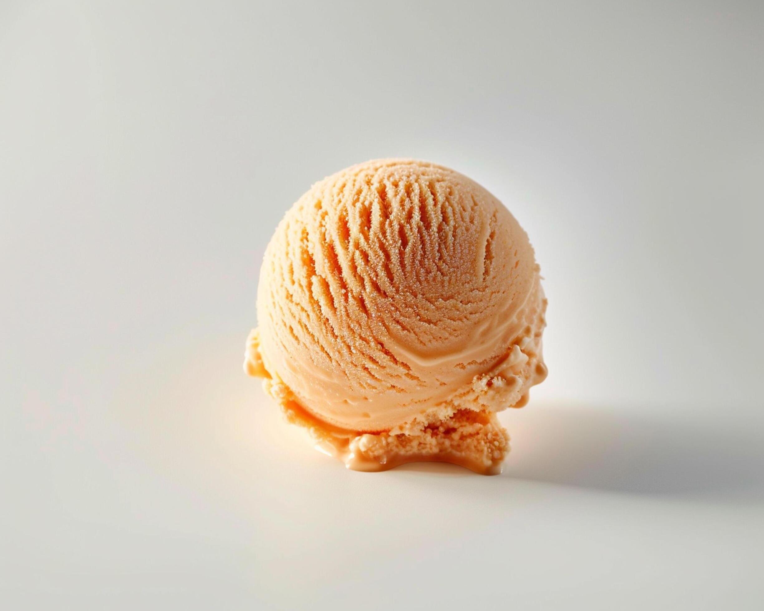 an orange ice cream ball sitting on top of a white surface Stock Free