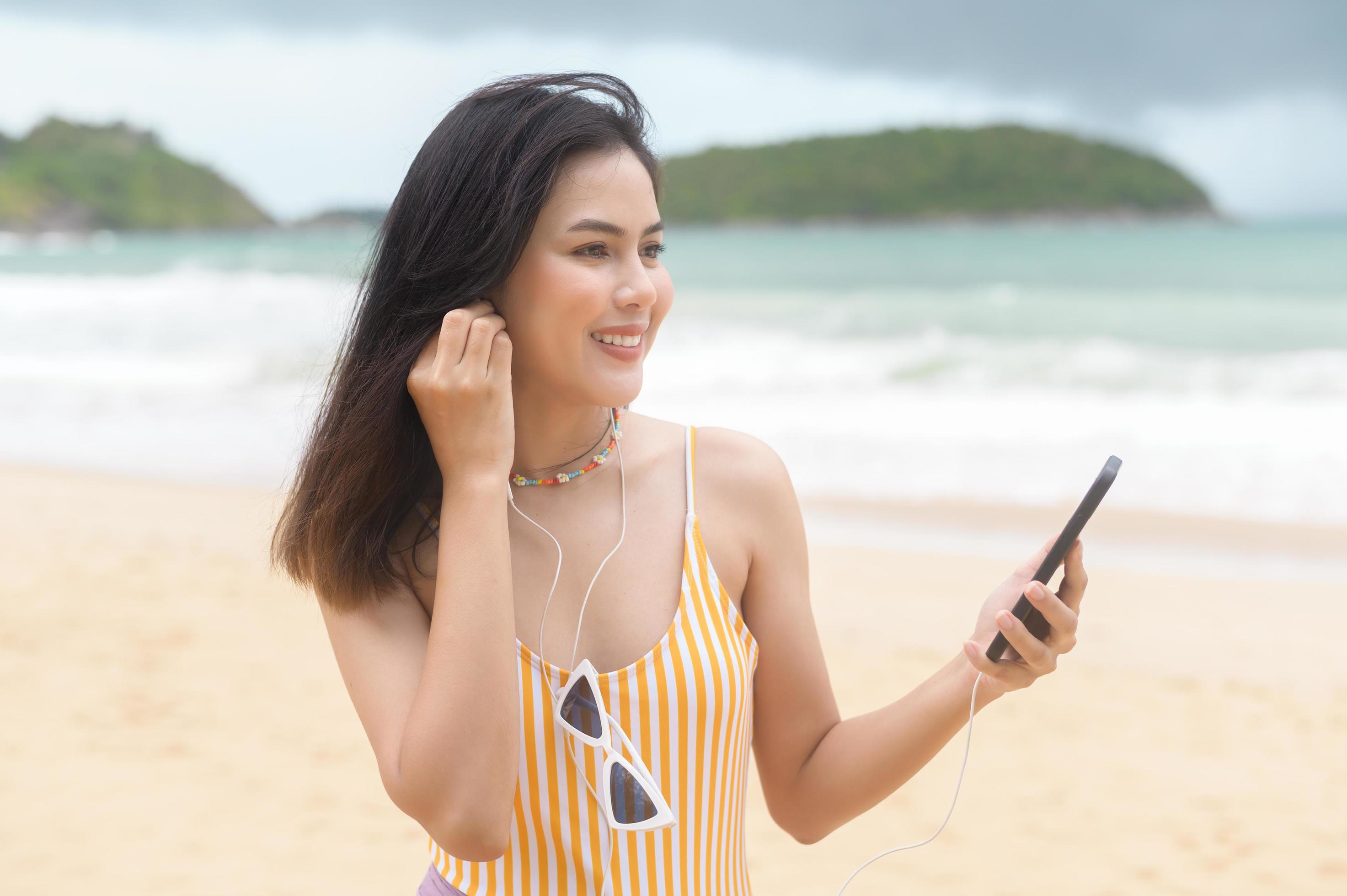 
									Young Beautiful woman in Bikini listening to music and using smartphone on the beach, Summer, vacation, holidays, Lifestyles concept. Stock Free