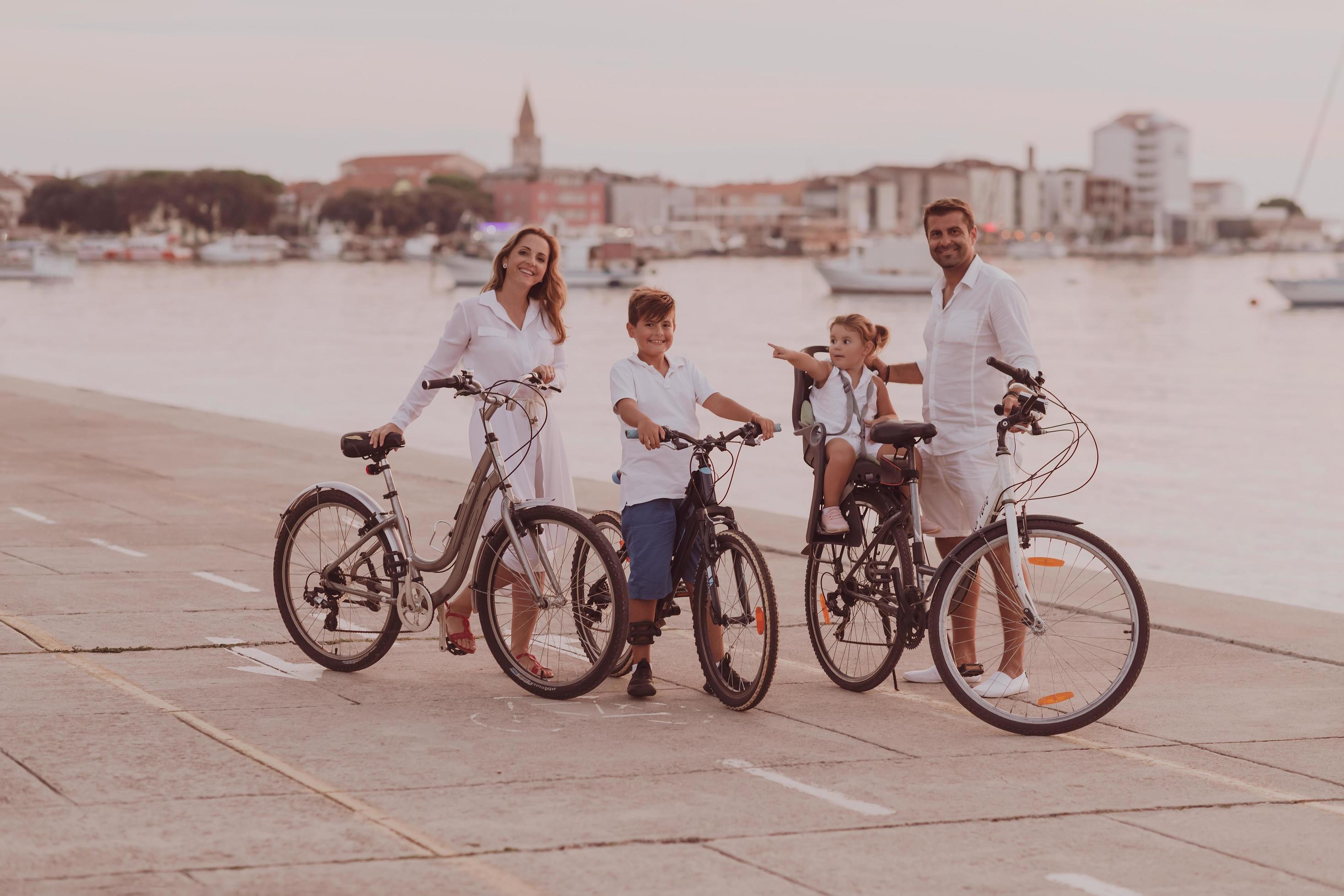 The happy family enjoys a beautiful morning by the sea riding a bike together and spending time together. The concept of a happy family Stock Free