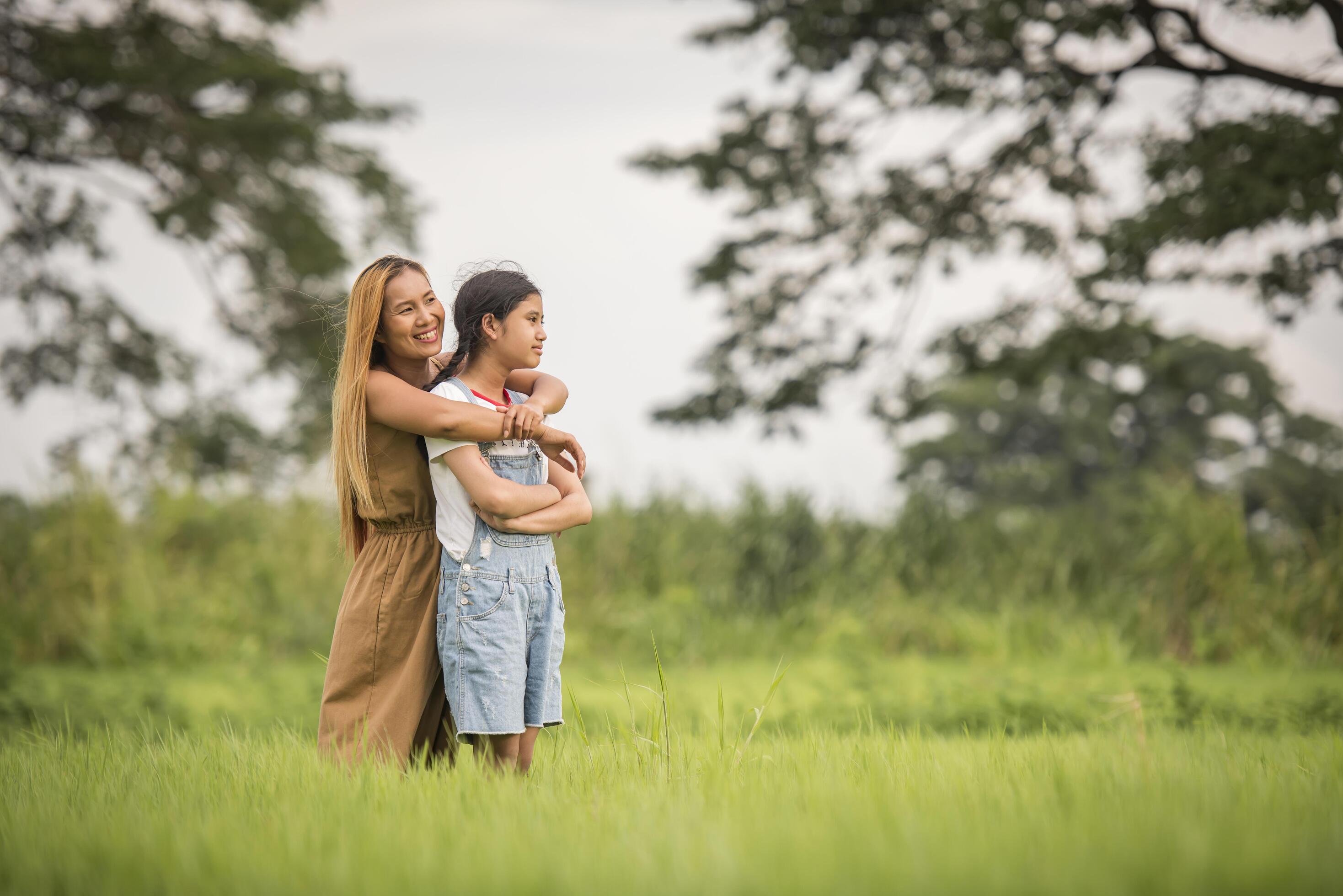 Mother and daughter standing happy in grass field Stock Free