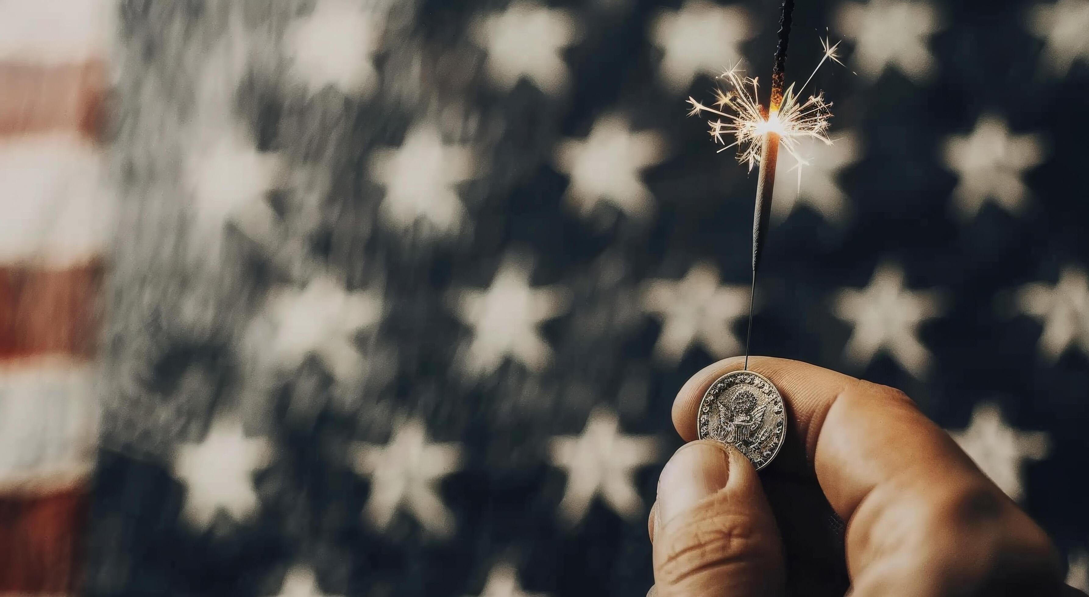 Hand Holding Sparkler Against Background of American Flag on Celebration Night Stock Free