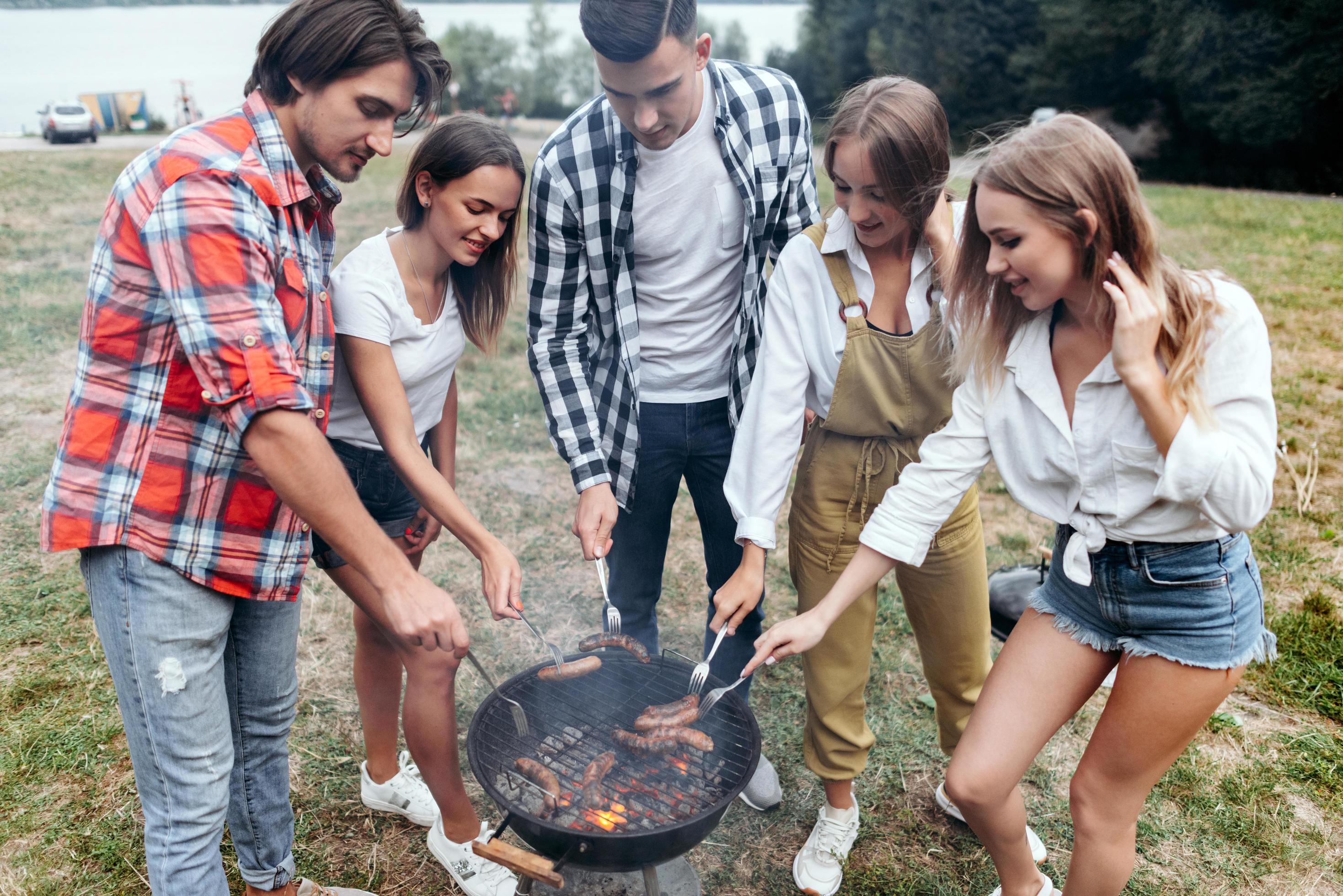 
									Friends in camp cooking a grill food and sausages Stock Free