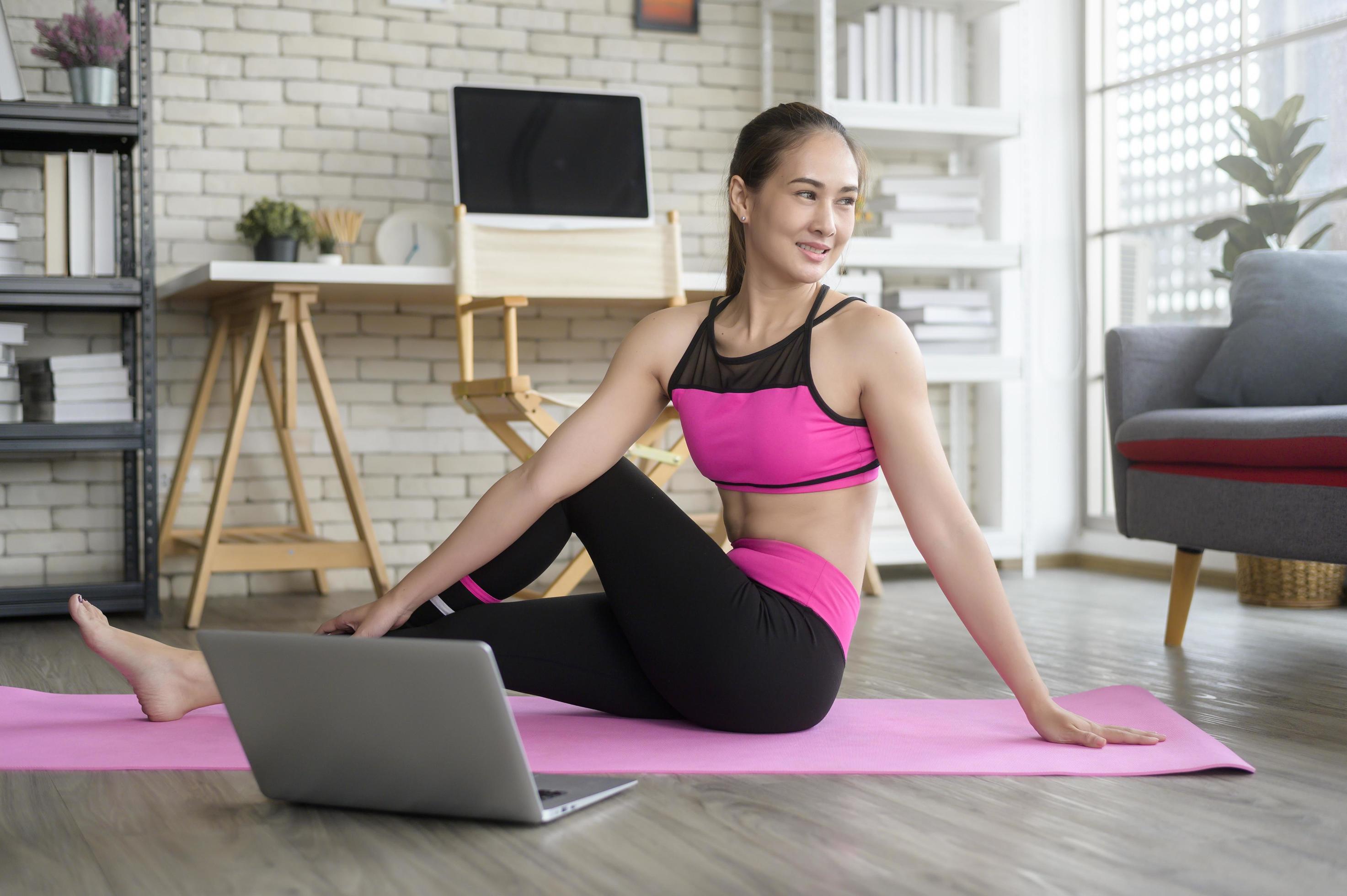 Fit young woman practicing yoga at home via online class with professional instructor, sport and healthy lifestyle concept. Stock Free