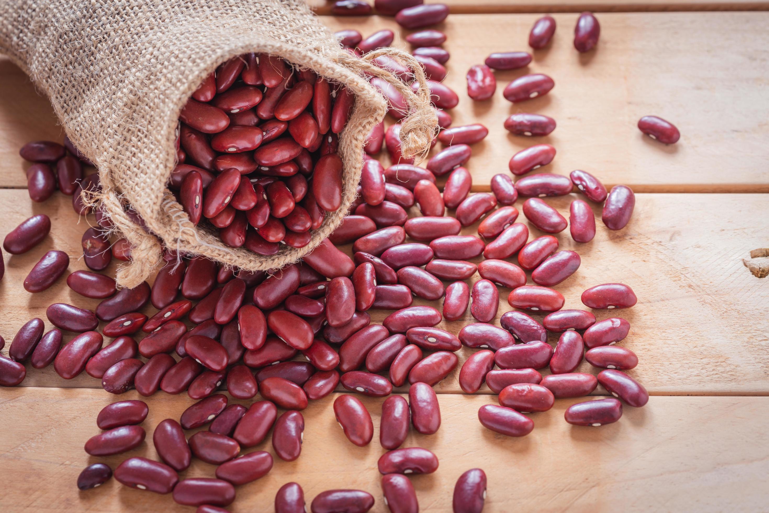 Red bean in sack on wooden background. Healthy food with adzuki seeds Stock Free