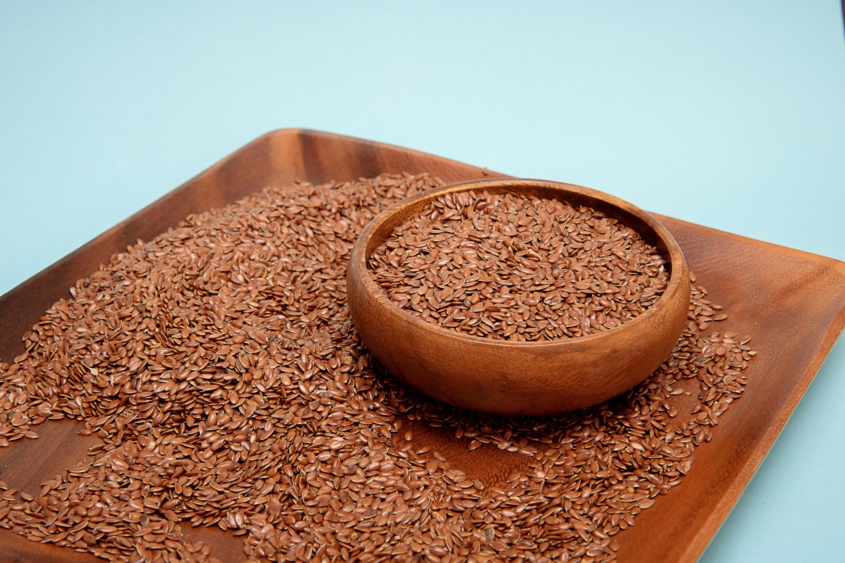 Flax seeds in a wooden bowl on a blue background,healthy food concept Stock Free