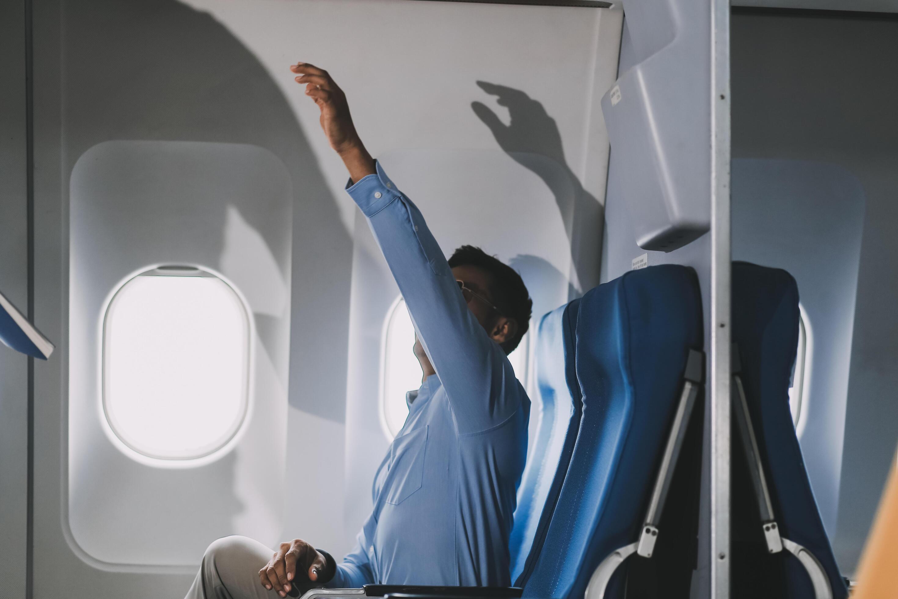 Asian businessman enjoying enjoys a coffee comfortable flight while sitting in the airplane cabin, Passengers near the window. Stock Free