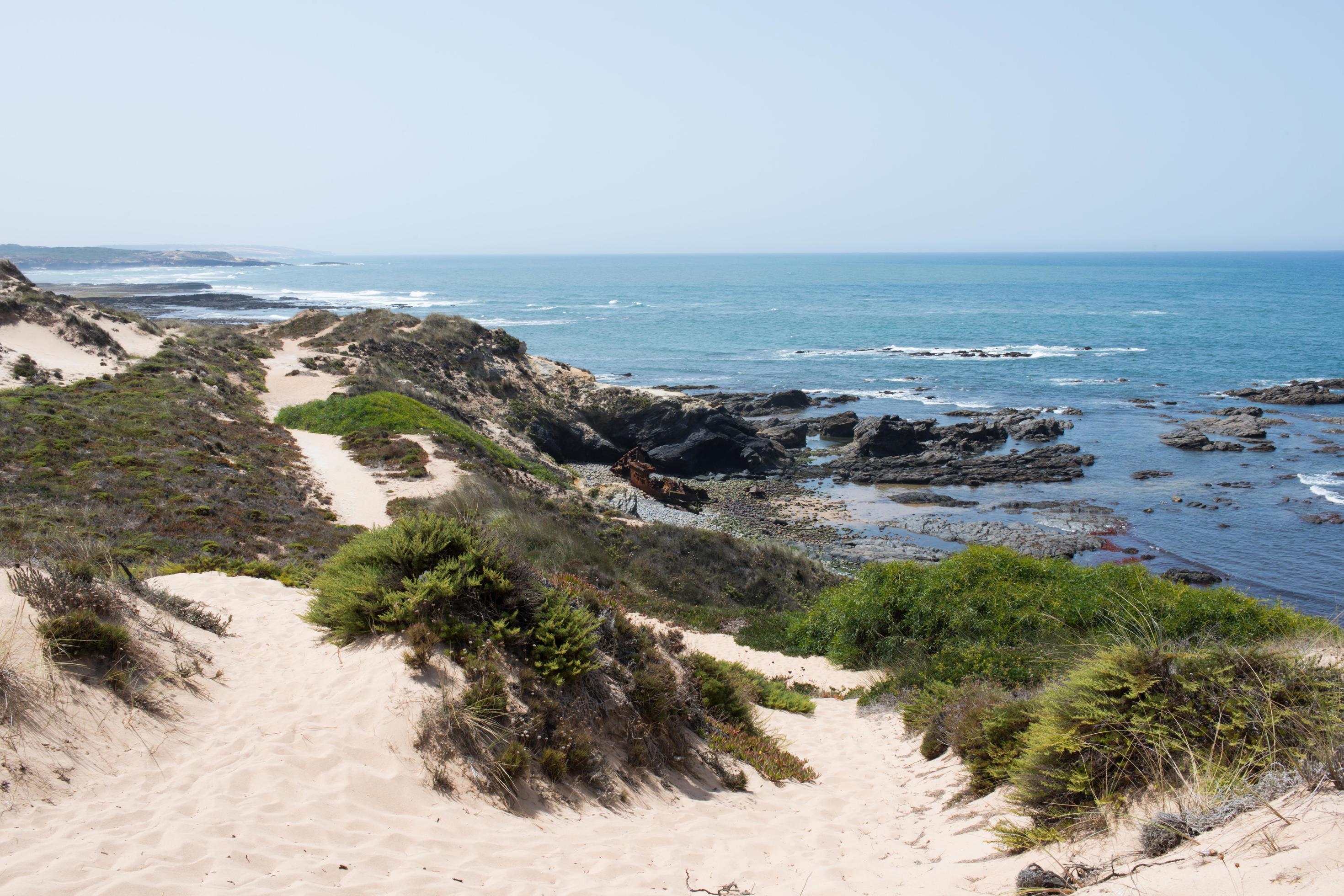 Beautiful coast of Alentejo. Sandy walking path along the coast. Rusty old nautical vessel. Sunny day. Stock Free