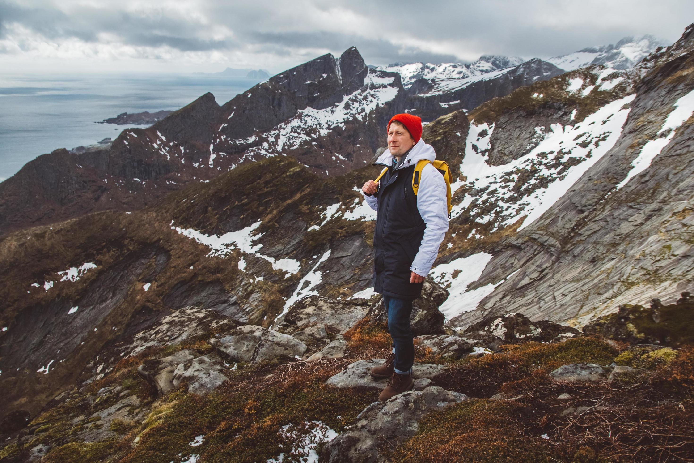 Man traveler hiking on Reinebringen mountain ridge in Norway lifestyle adventure traveling Stock Free