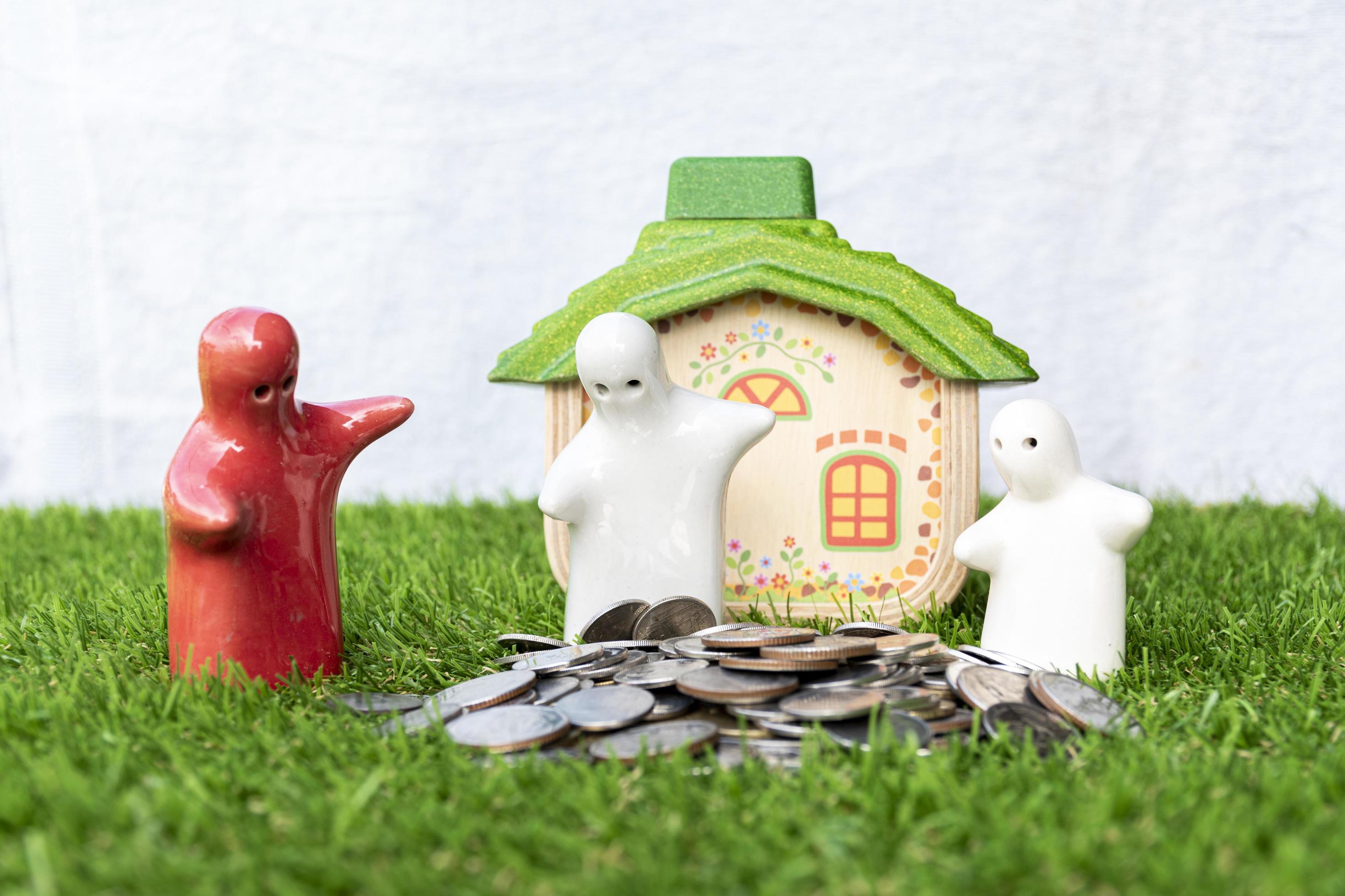 Mock up family statue and coins on grass floor with house model background Stock Free