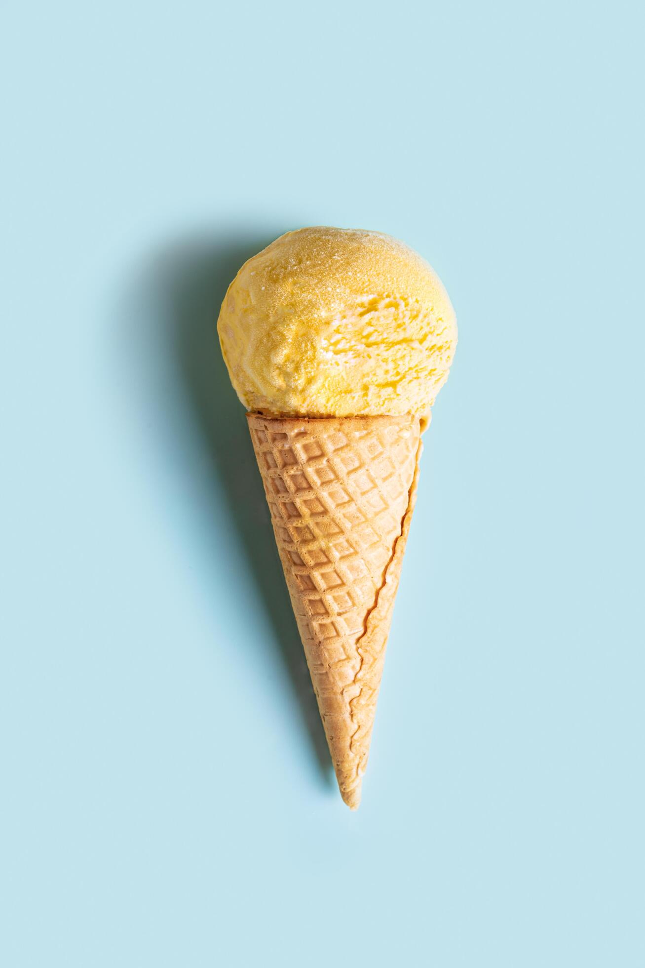 Yellow ice cream cone on blue background Stock Free